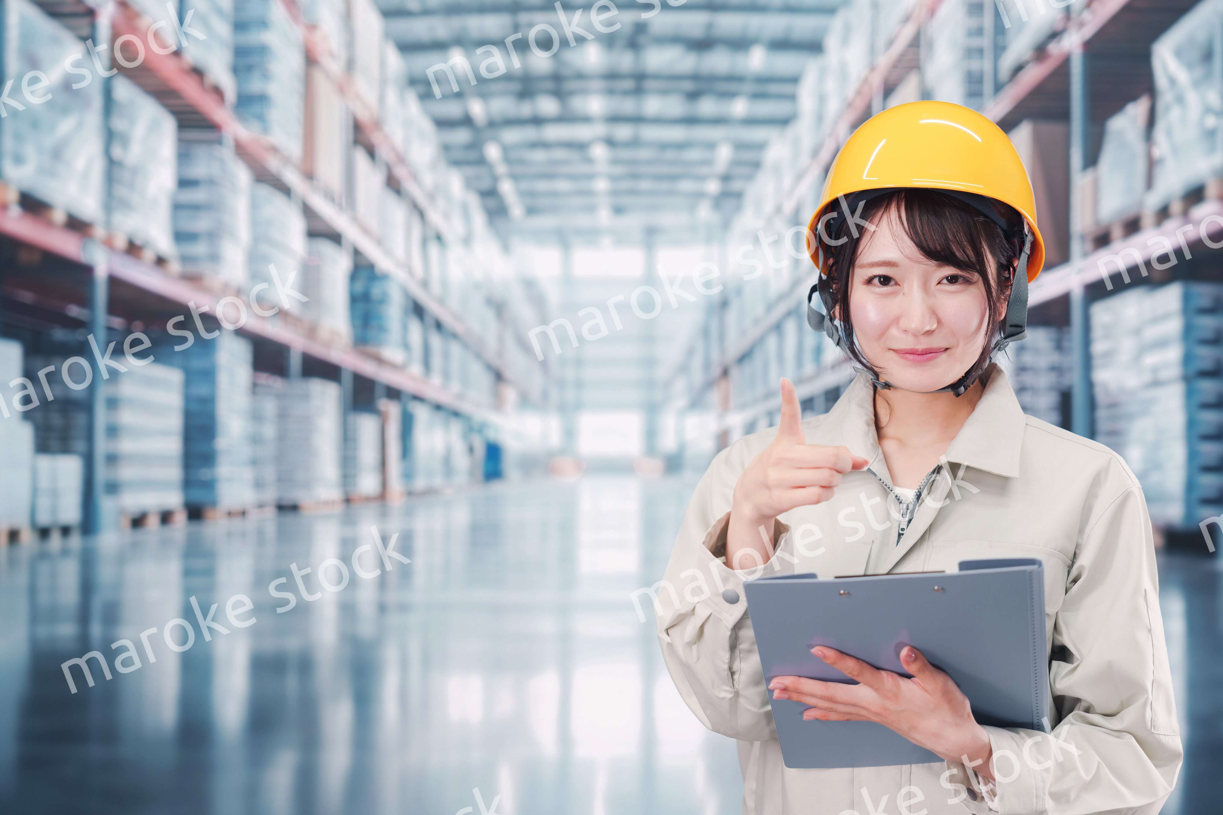 大きな物流倉庫で働くヘルメットを被った若い女性