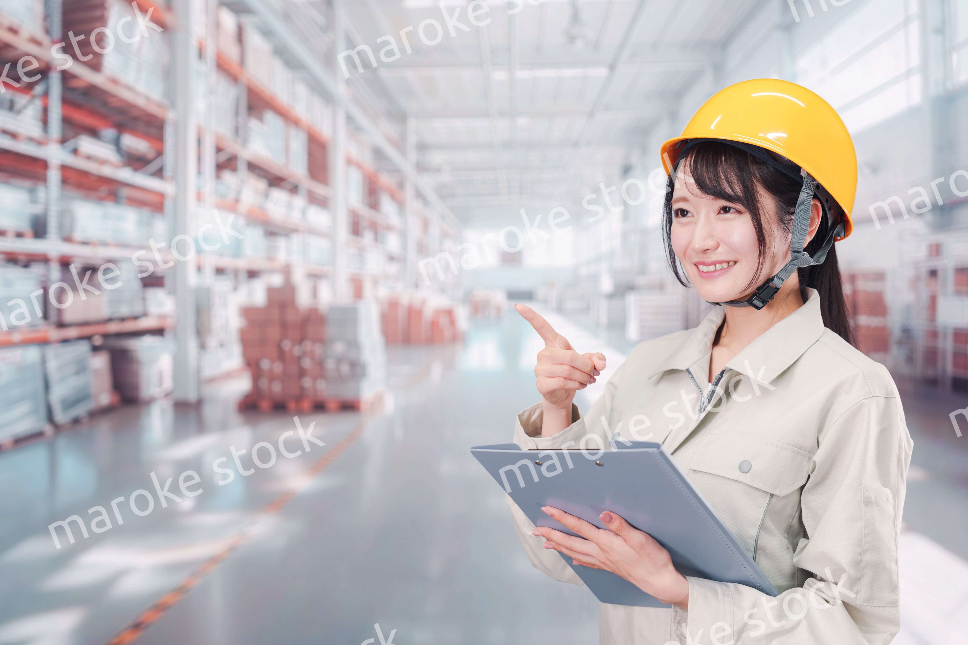 大きな物流倉庫で働くヘルメットを被った若い女性