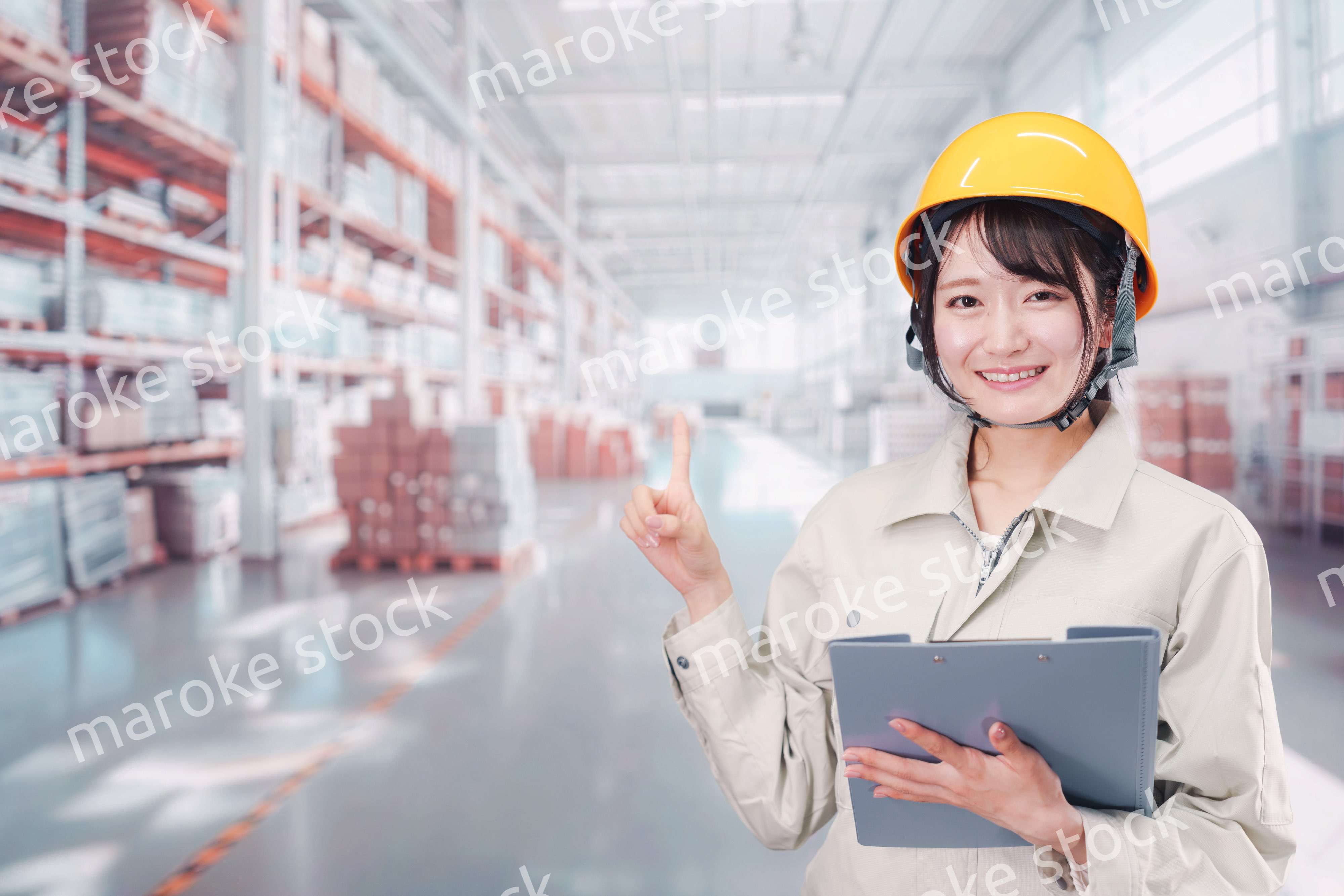 大きな物流倉庫で働くヘルメットを被った若い女性