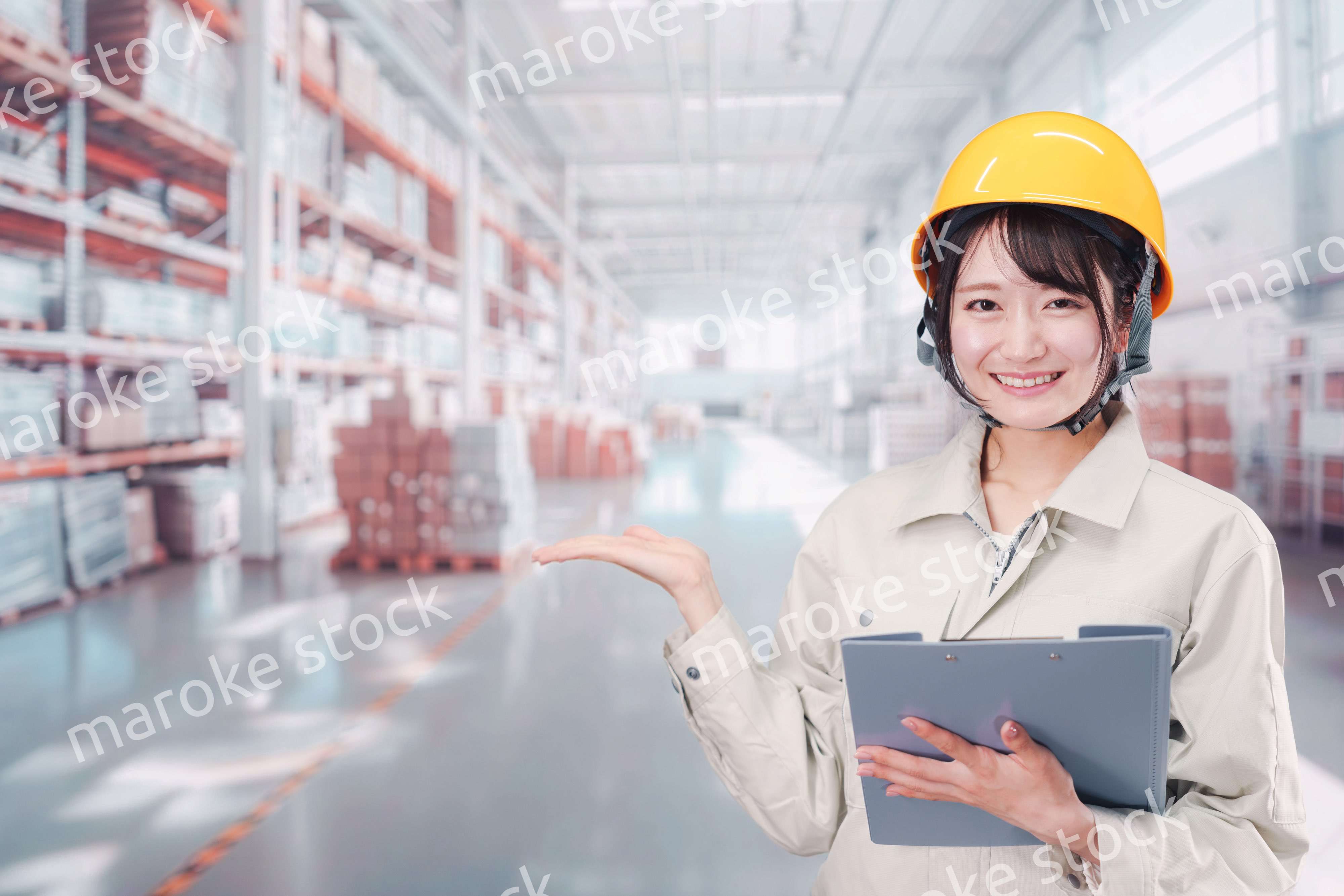 大きな物流倉庫で働くヘルメットを被った若い女性