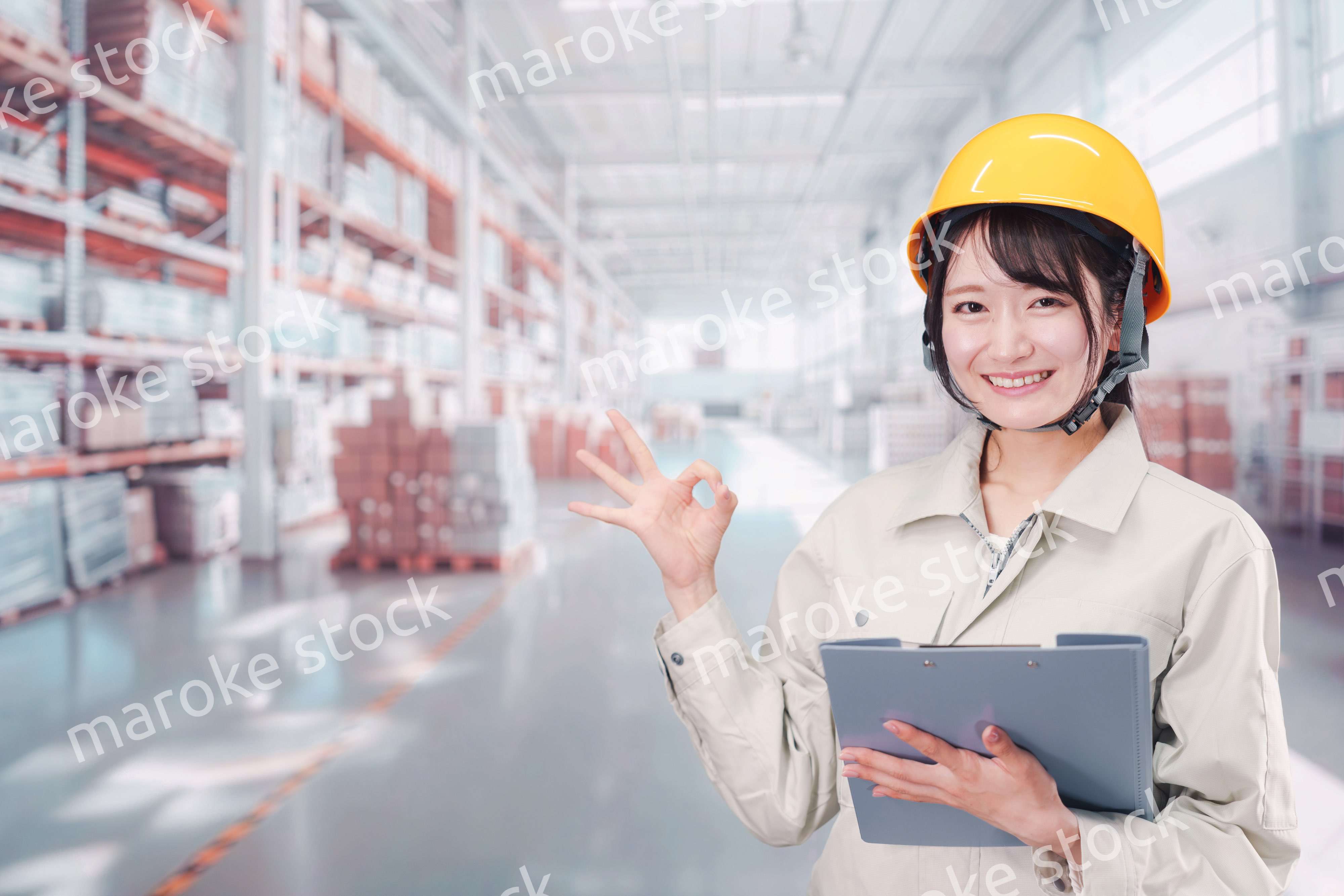 大きな物流倉庫で働くヘルメットを被った若い女性