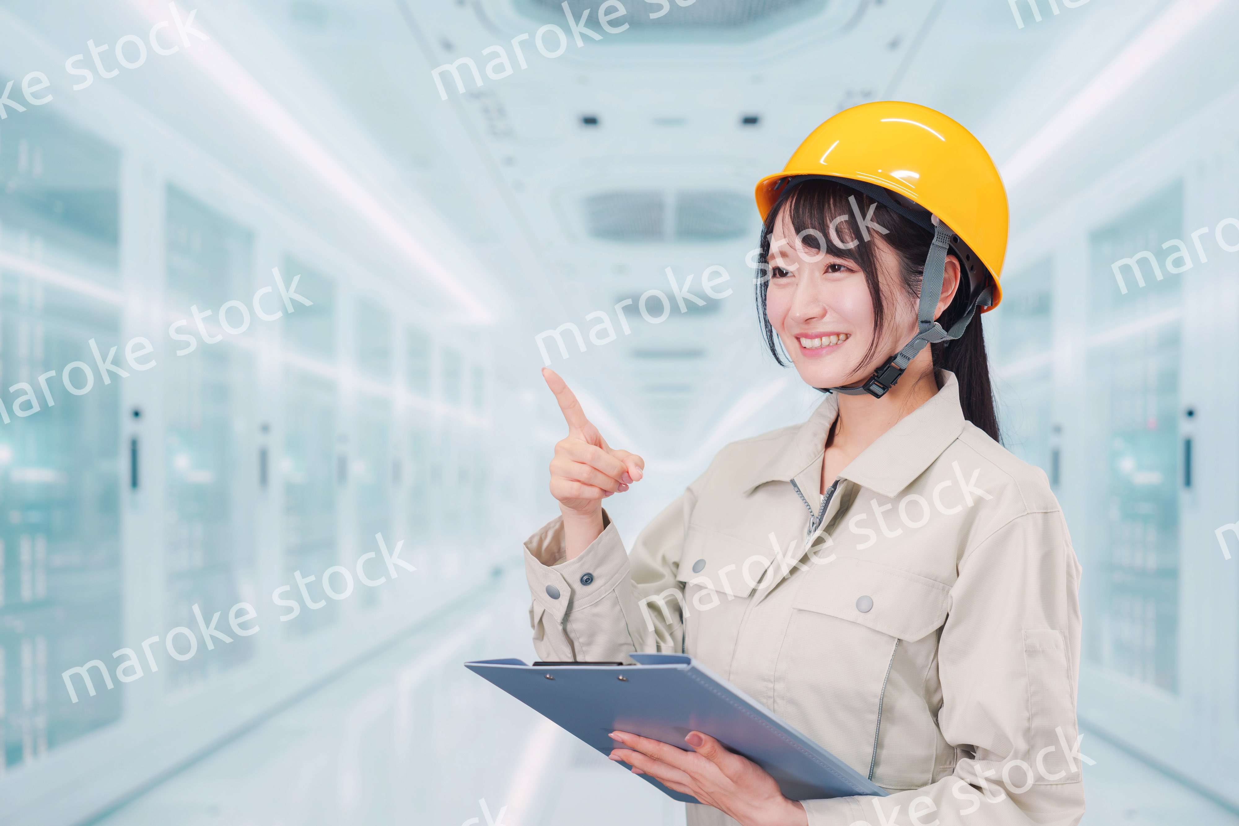 データセンターのサーバールームで働く作業服姿の女性