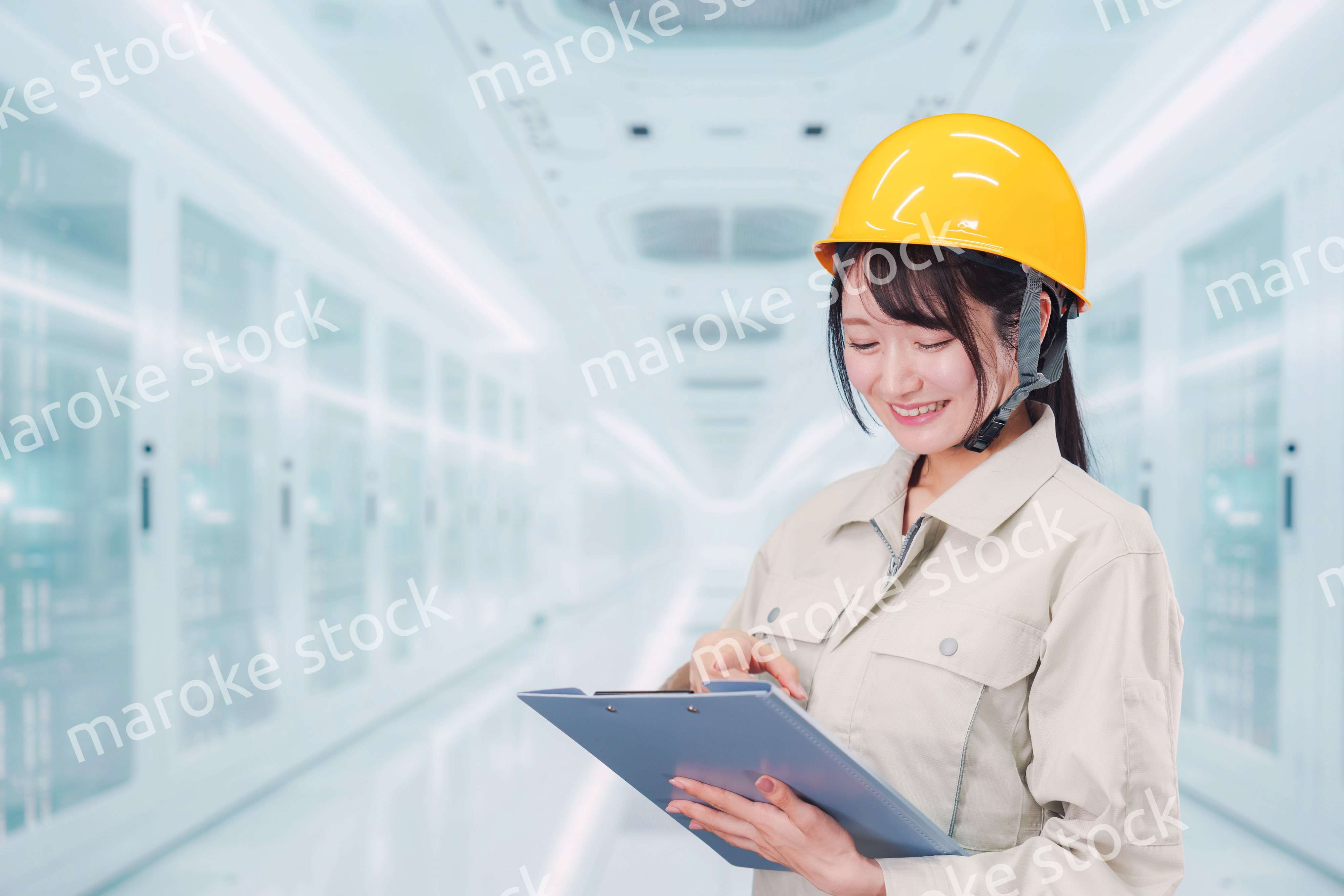 データセンターのサーバールームで働く作業服姿の女性