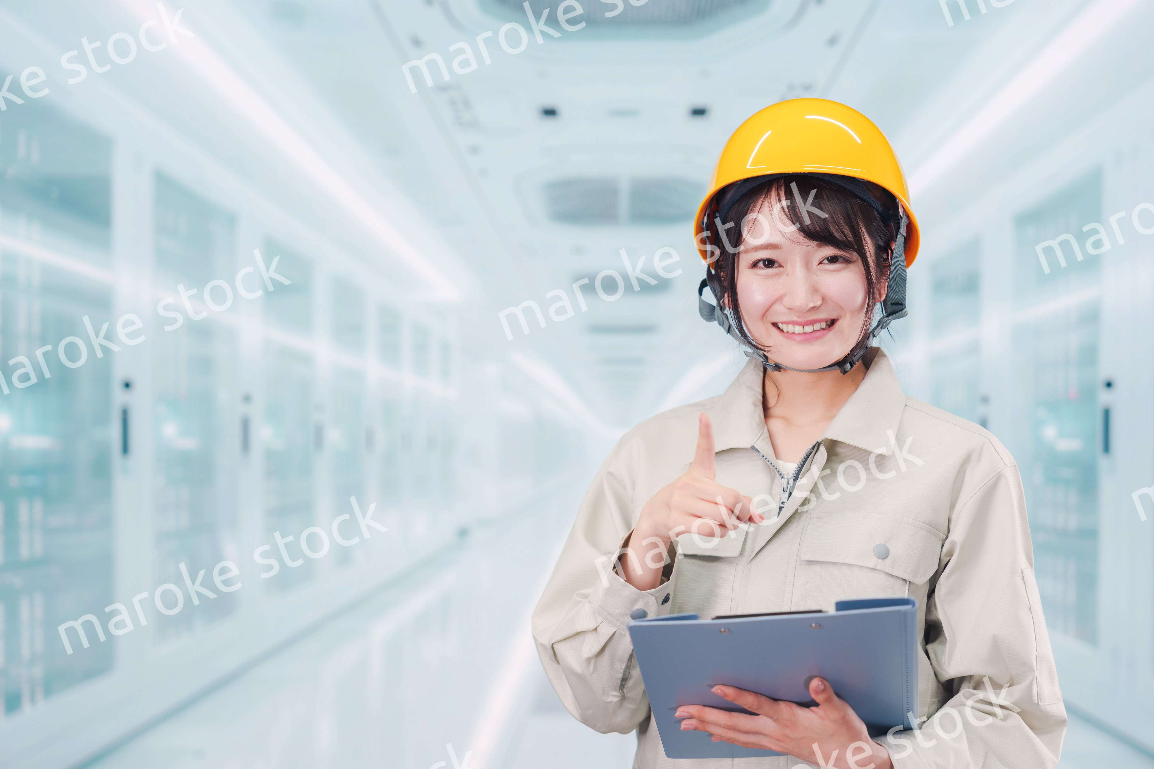 データセンターのサーバールームで働く作業服姿の女性