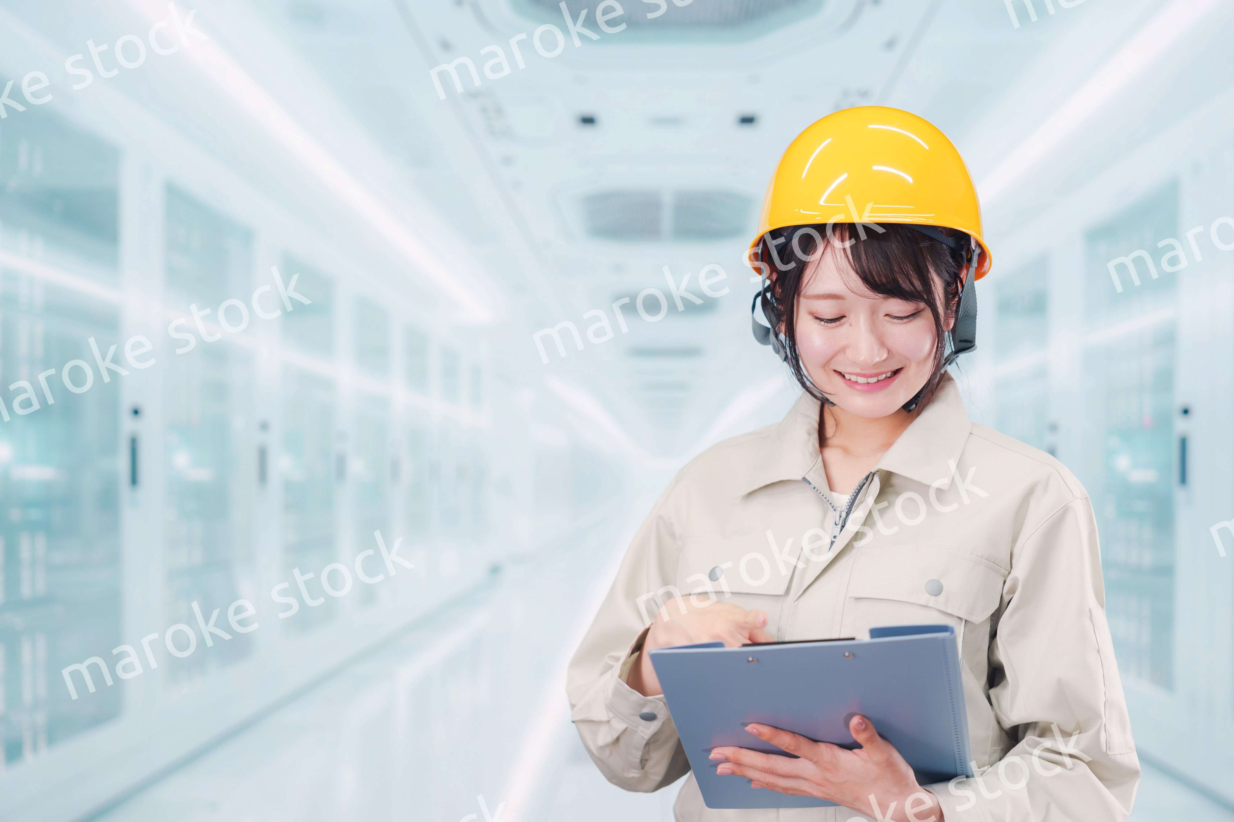データセンターのサーバールームで働く作業服姿の女性