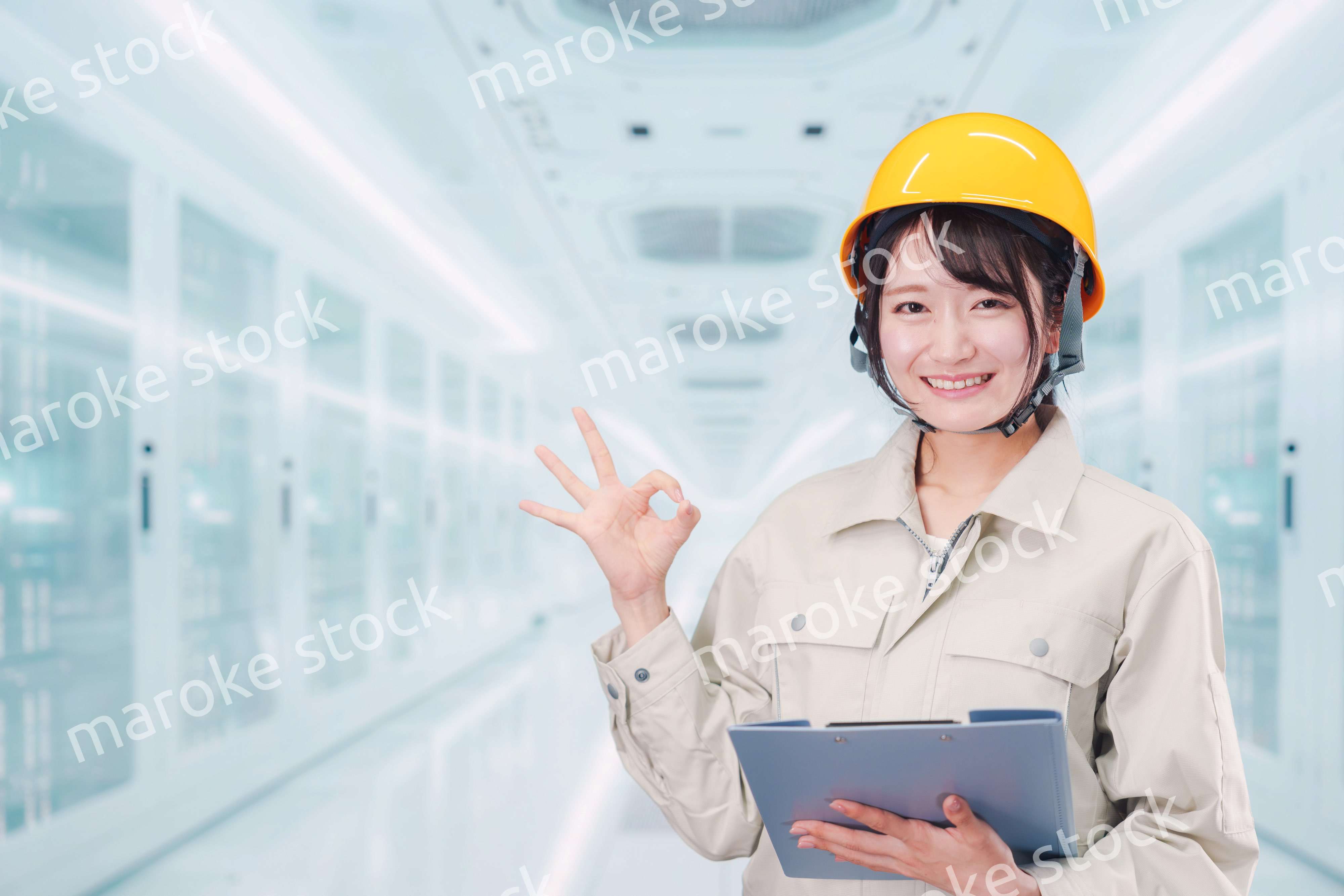 データセンターのサーバールームで働く作業服姿の女性