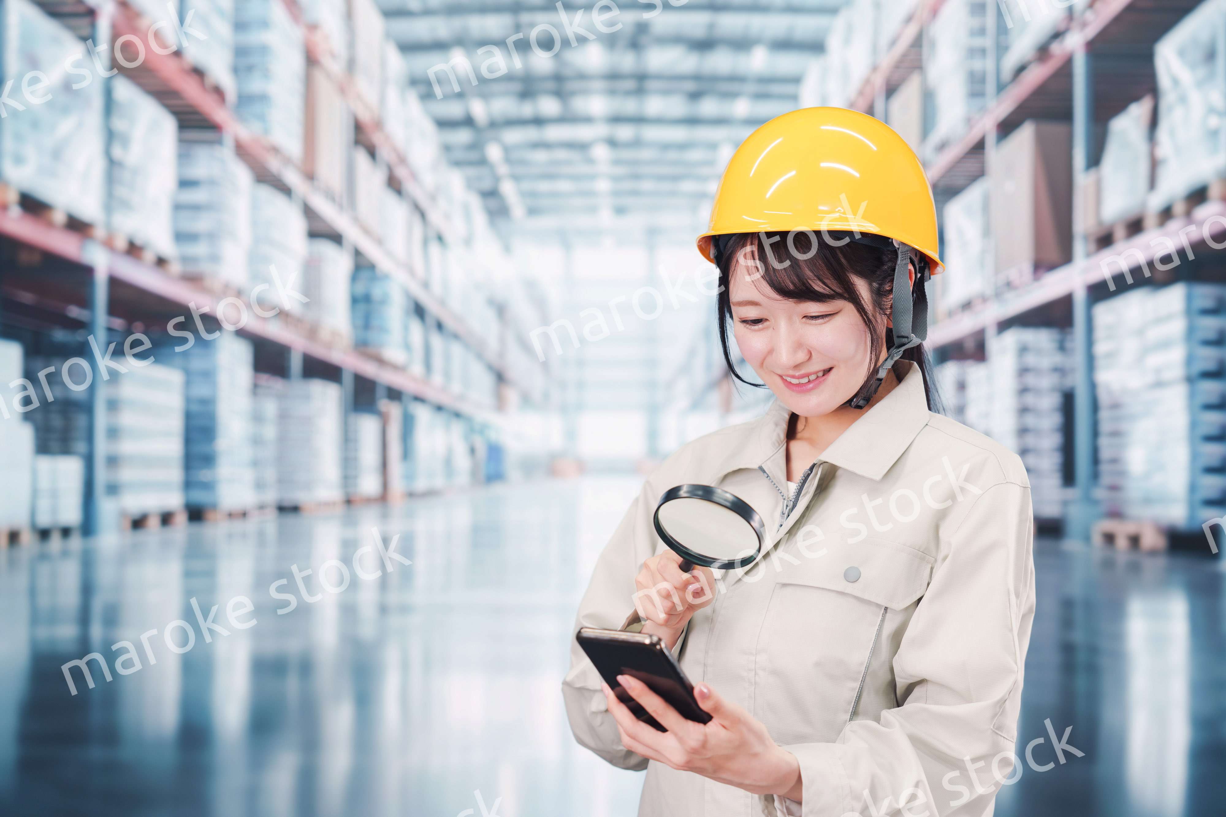 倉庫で在庫を探す作業服姿の女性