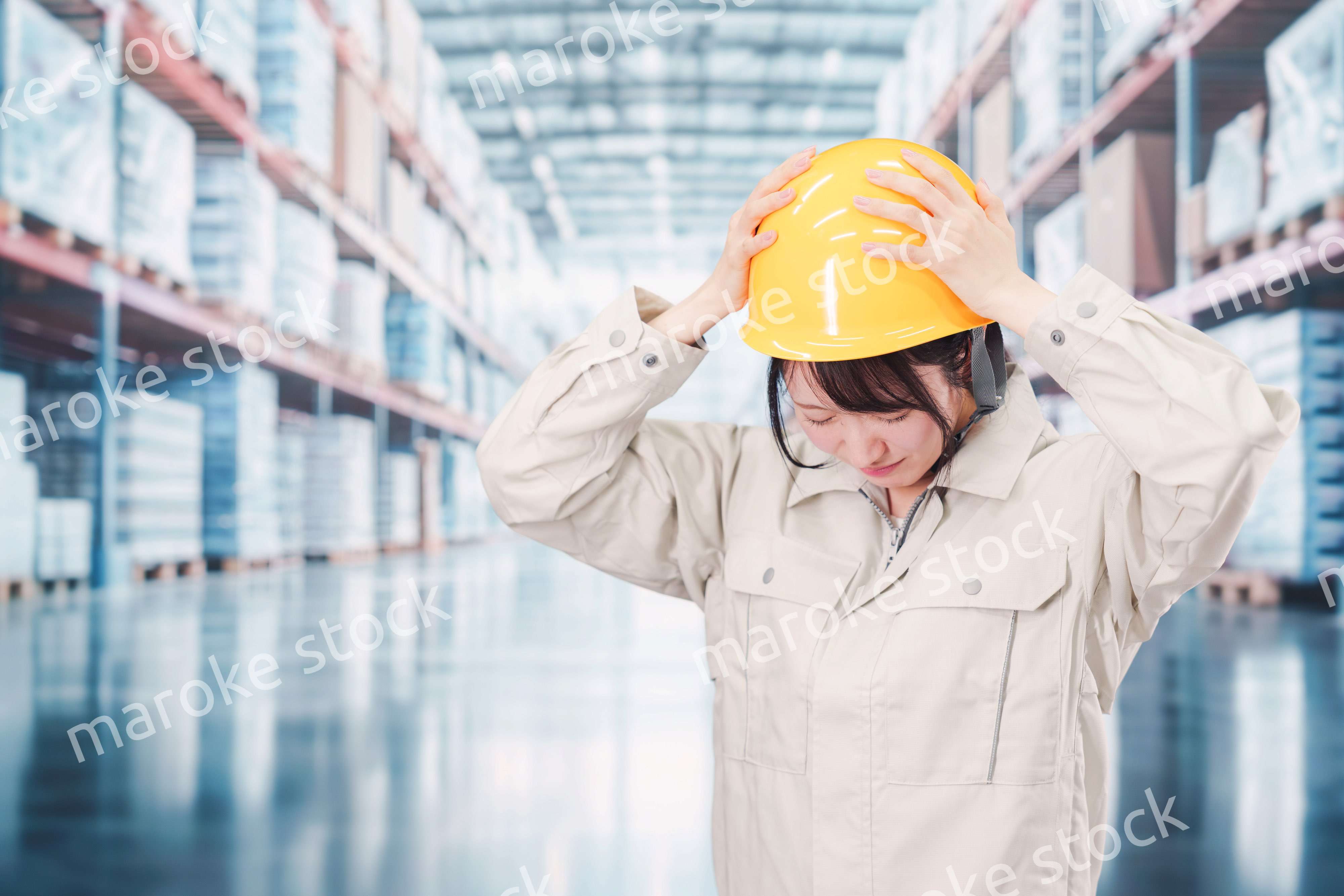 倉庫の中で頭を抱える女性の従業員