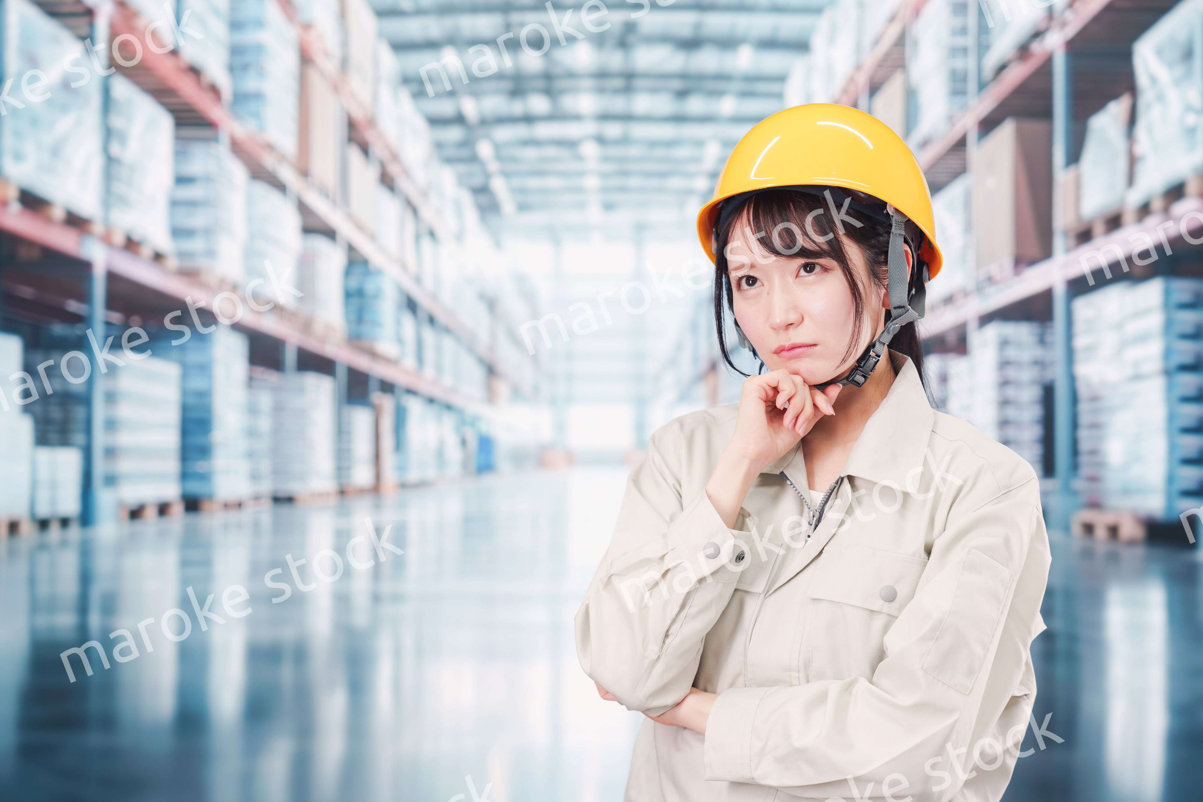 倉庫の中で頭を抱える女性の従業員