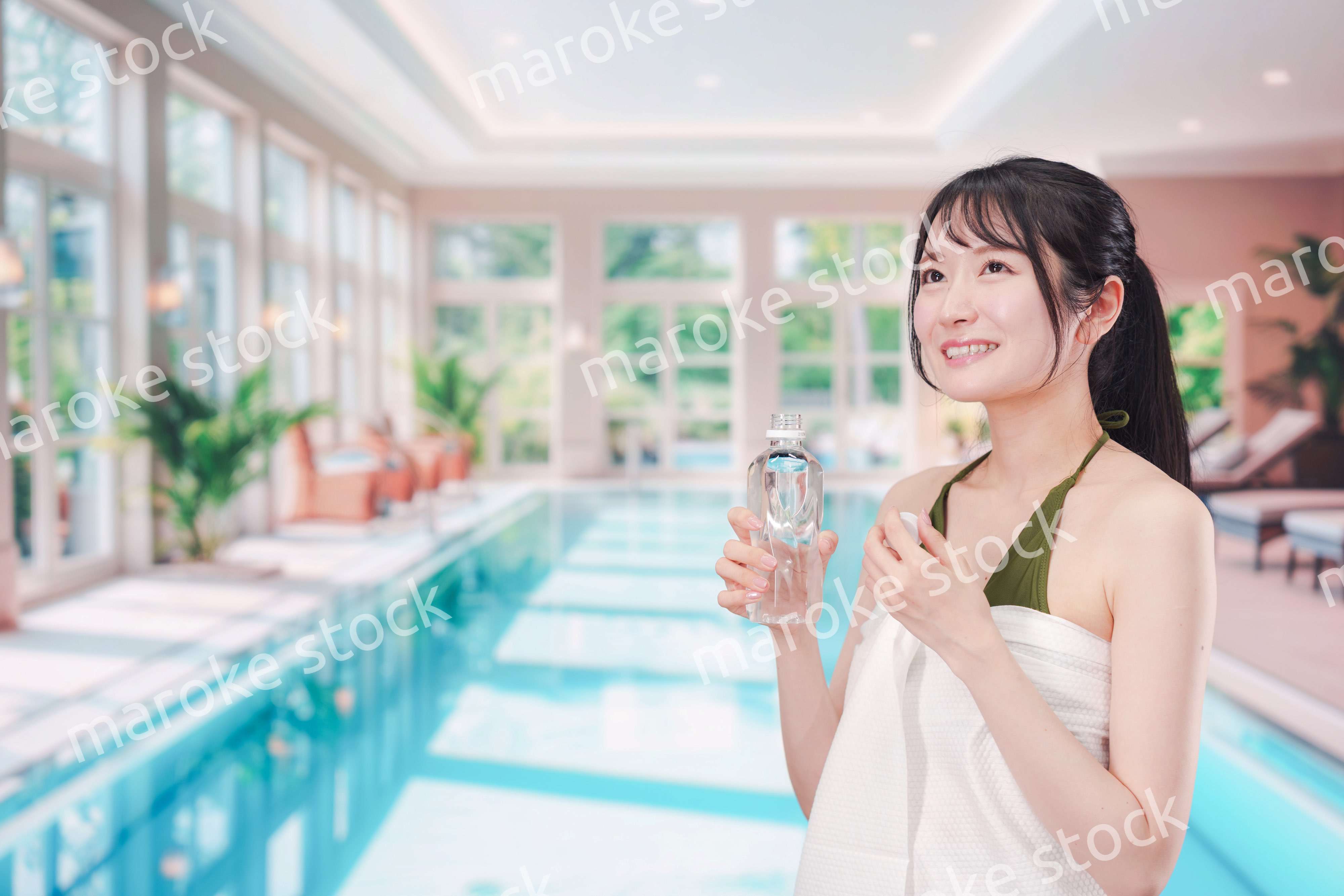 プールで水を飲んでクールダウンする水着姿の女性