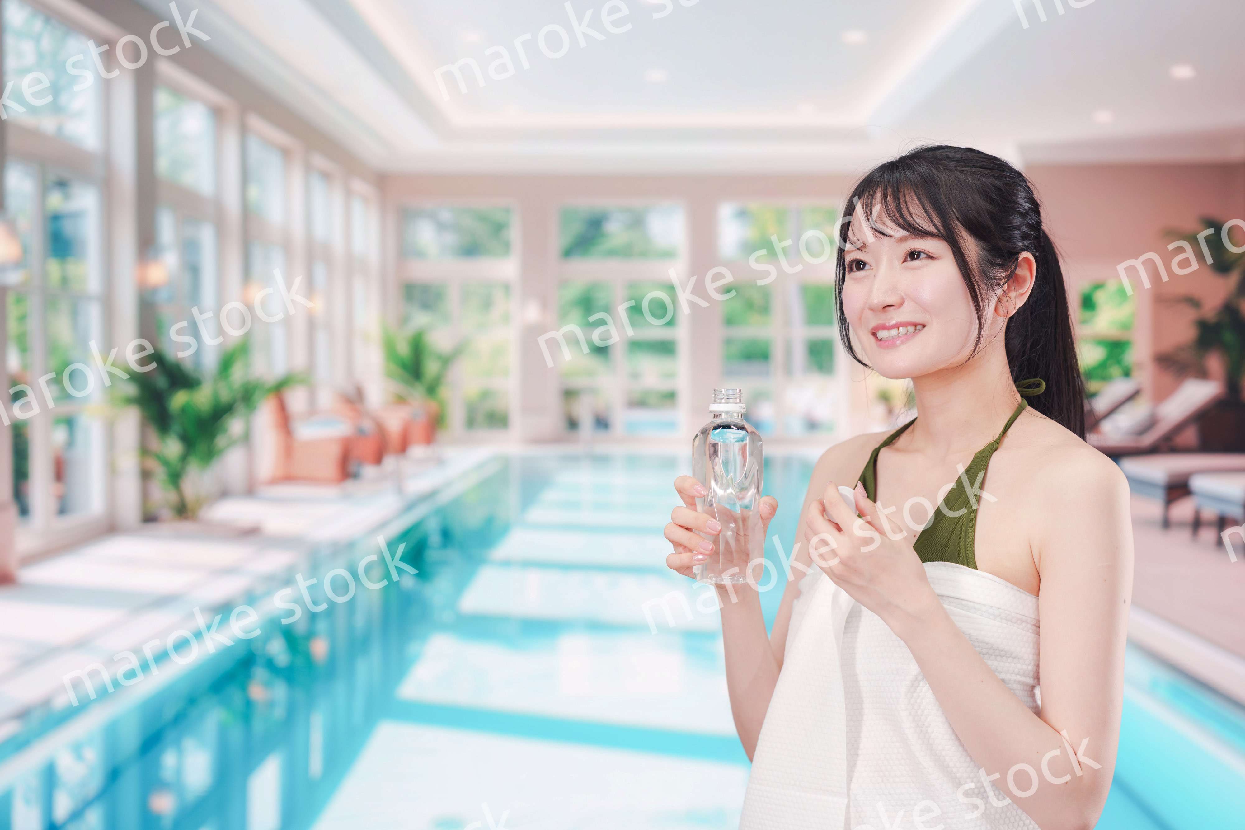 プールで水を飲んでクールダウンする水着姿の女性