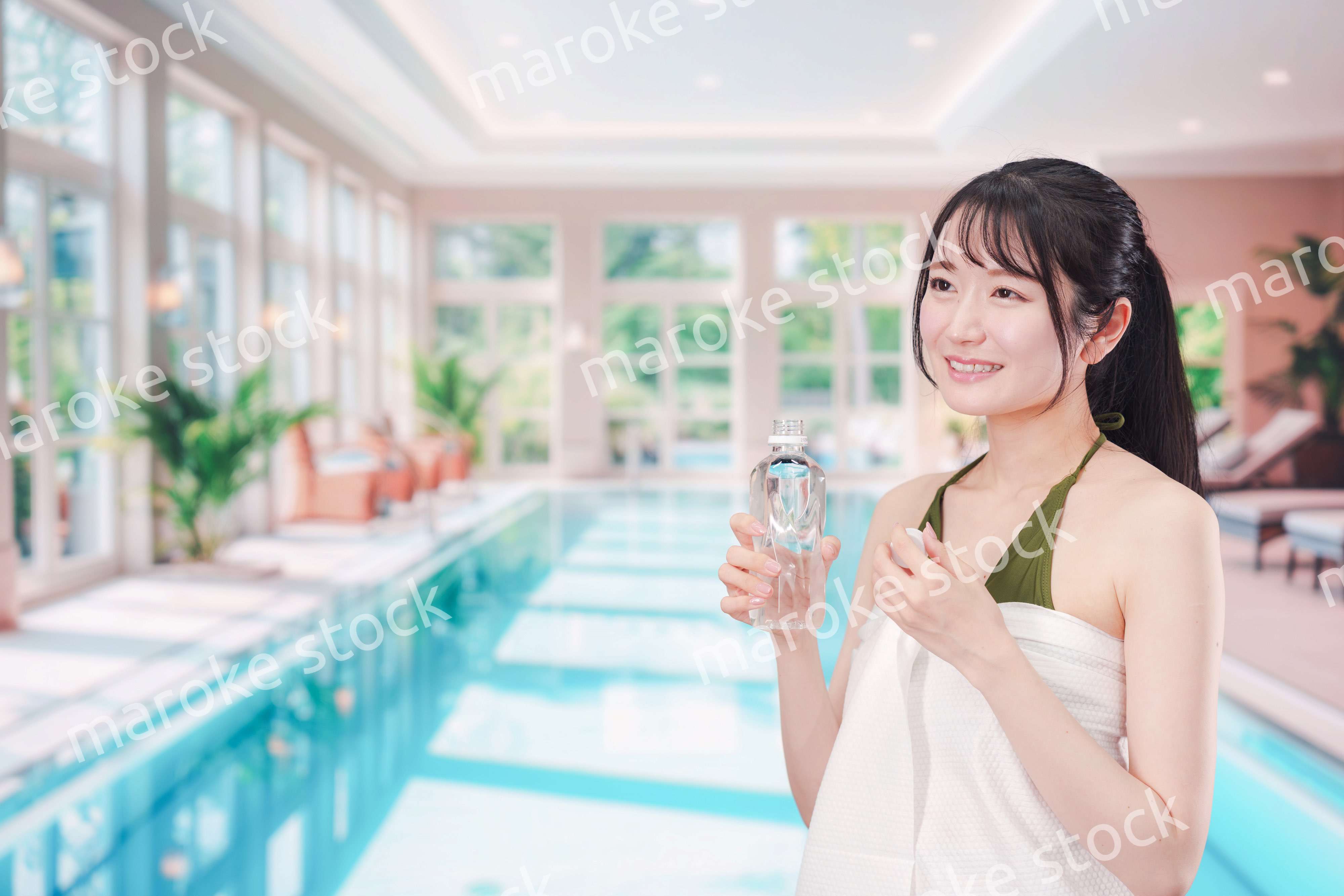 プールで水を飲んでクールダウンする水着姿の女性