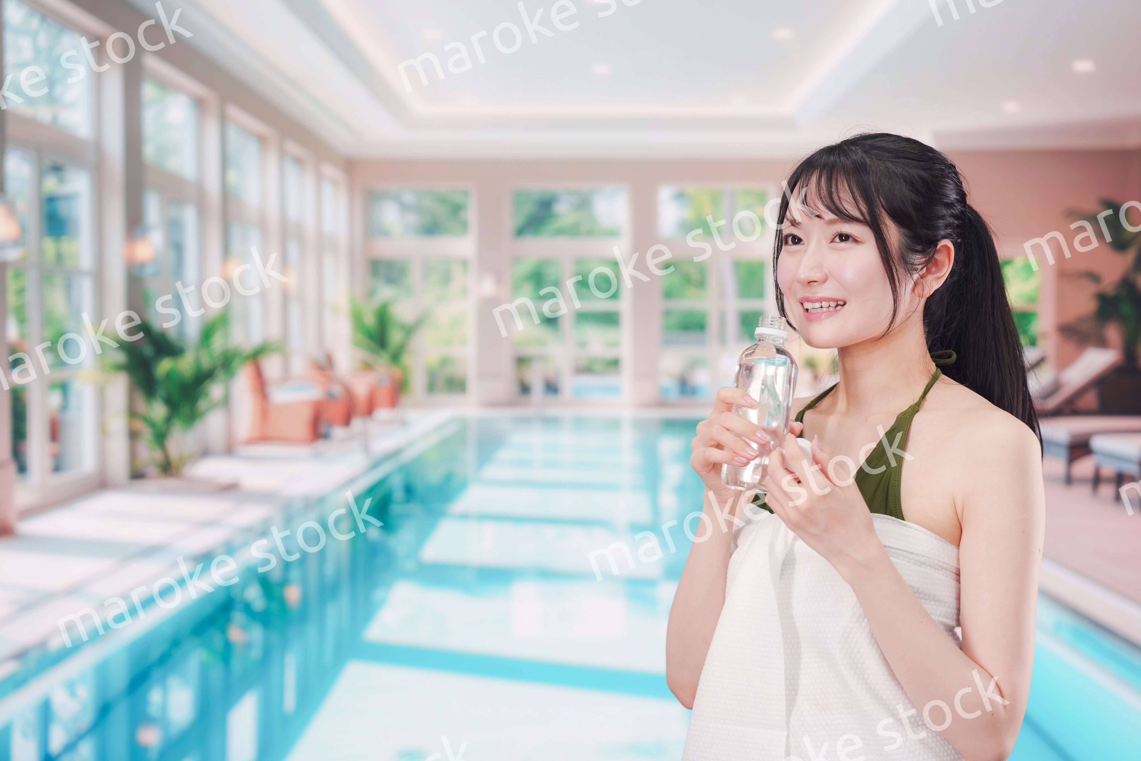 プールで水を飲んでクールダウンする水着姿の女性