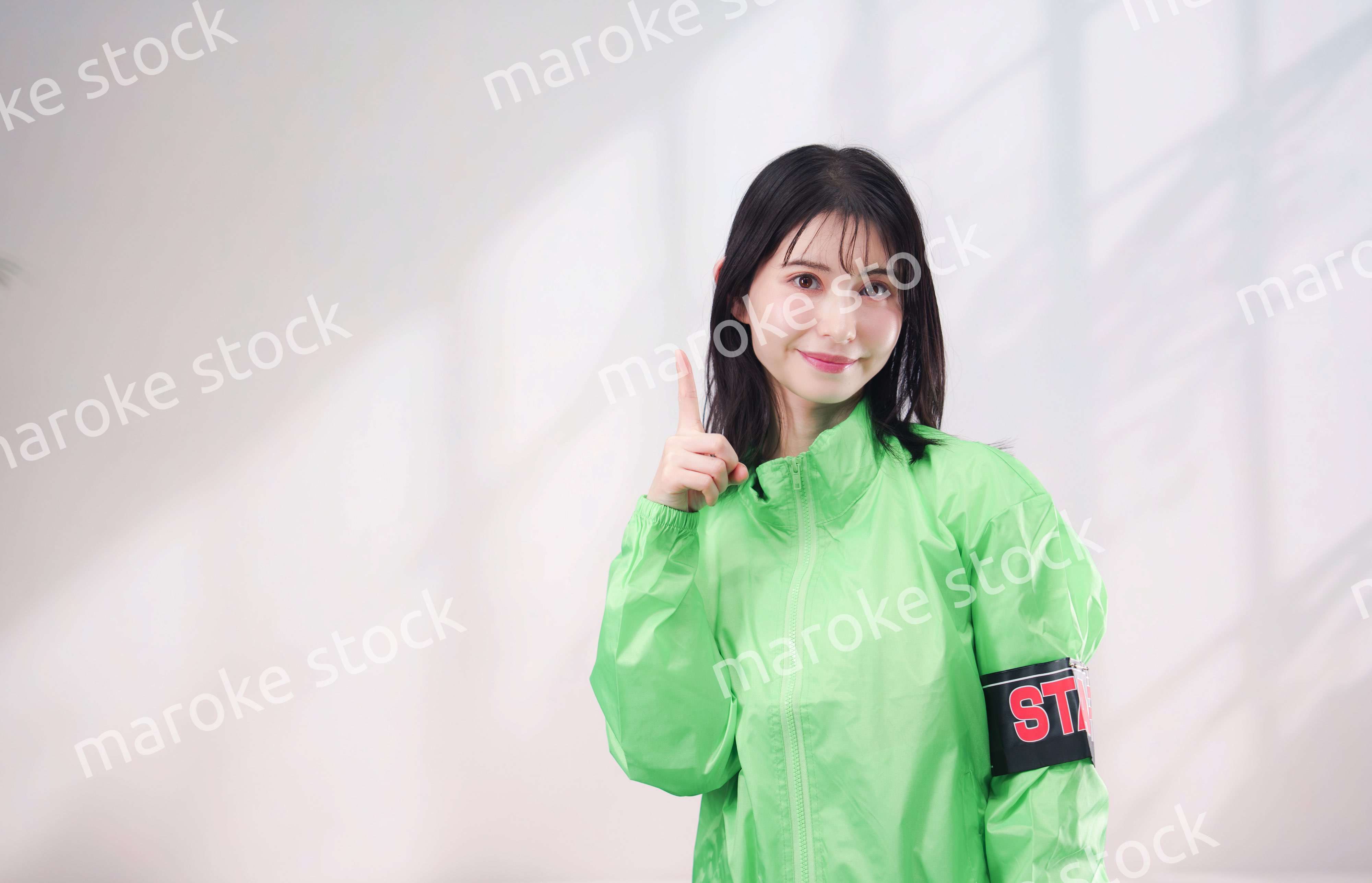 スタッフジャンパーをきた笑顔のイベントスタッフ（シンプル背景）