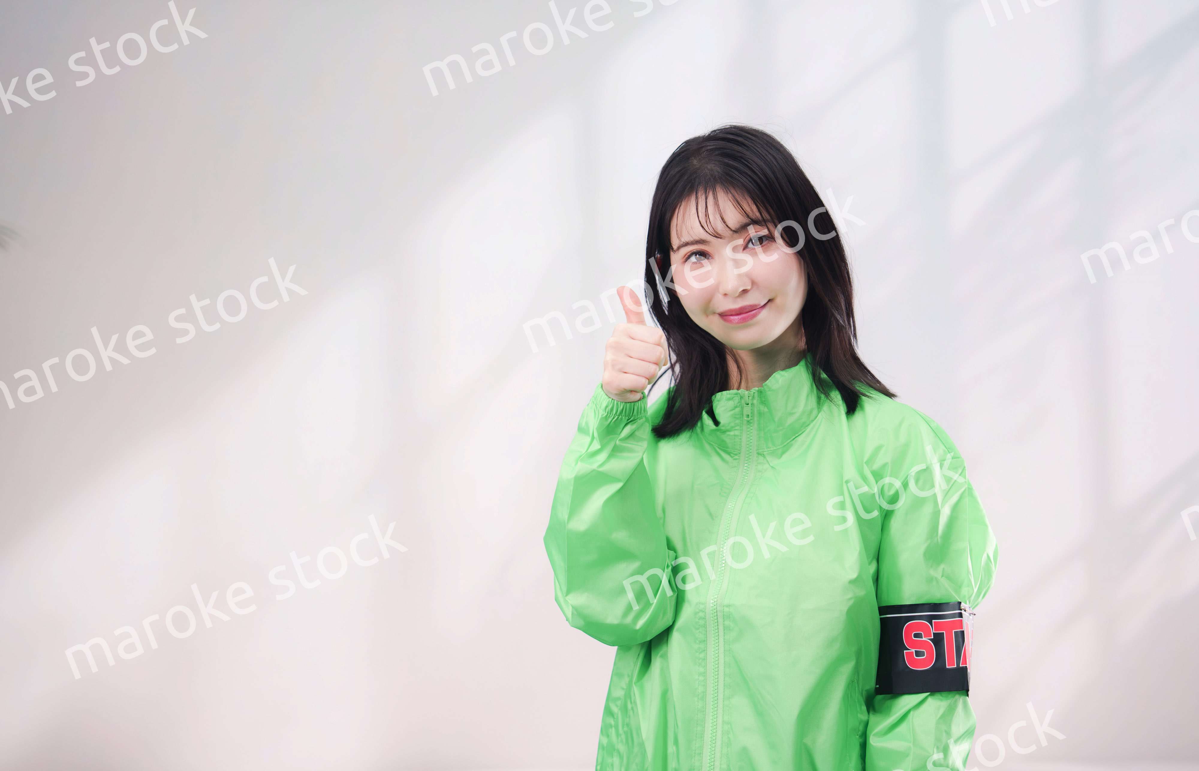 スタッフジャンパーをきた笑顔のイベントスタッフ（シンプル背景）