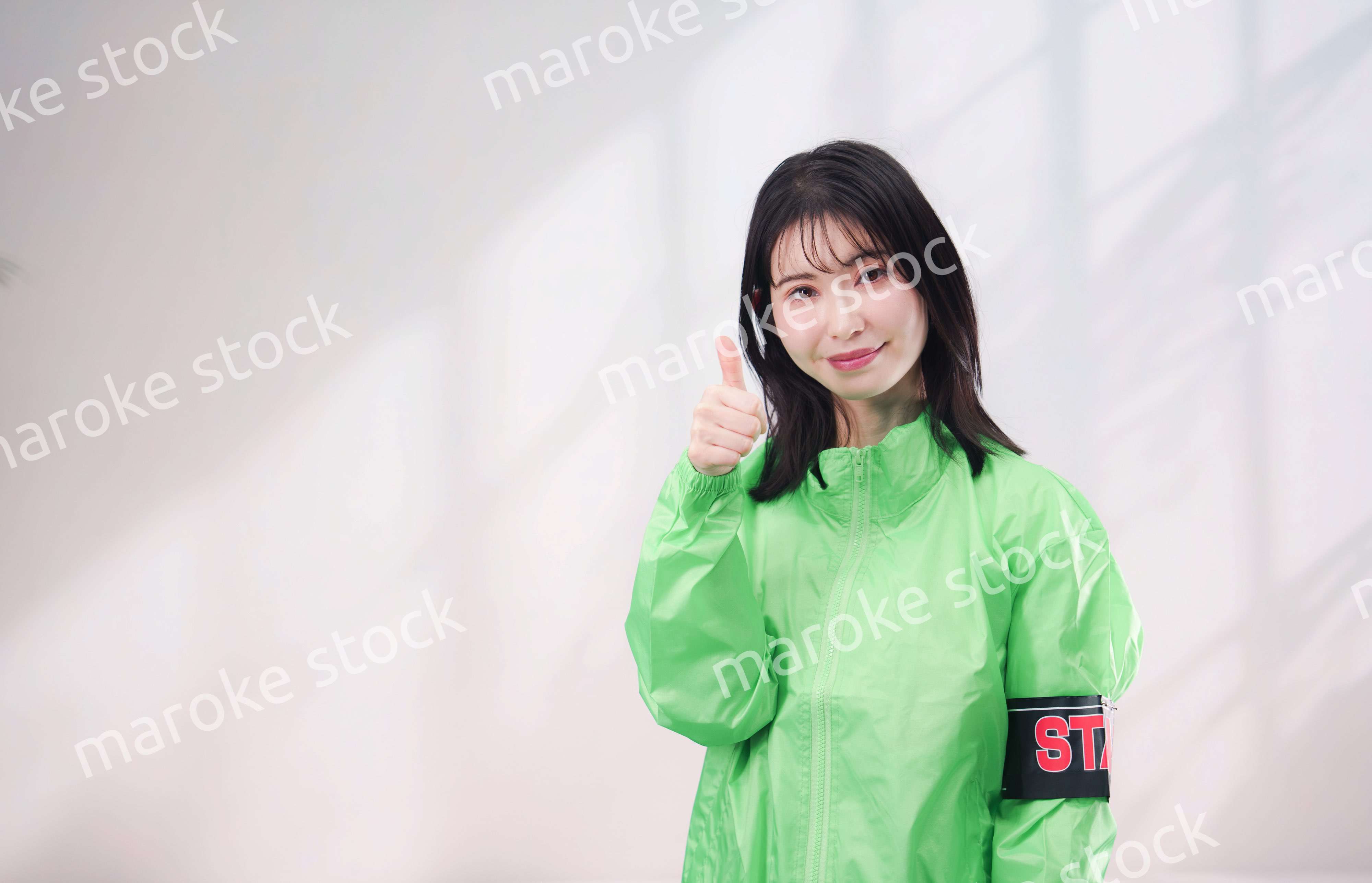 スタッフジャンパーをきた笑顔のイベントスタッフ（シンプル背景）