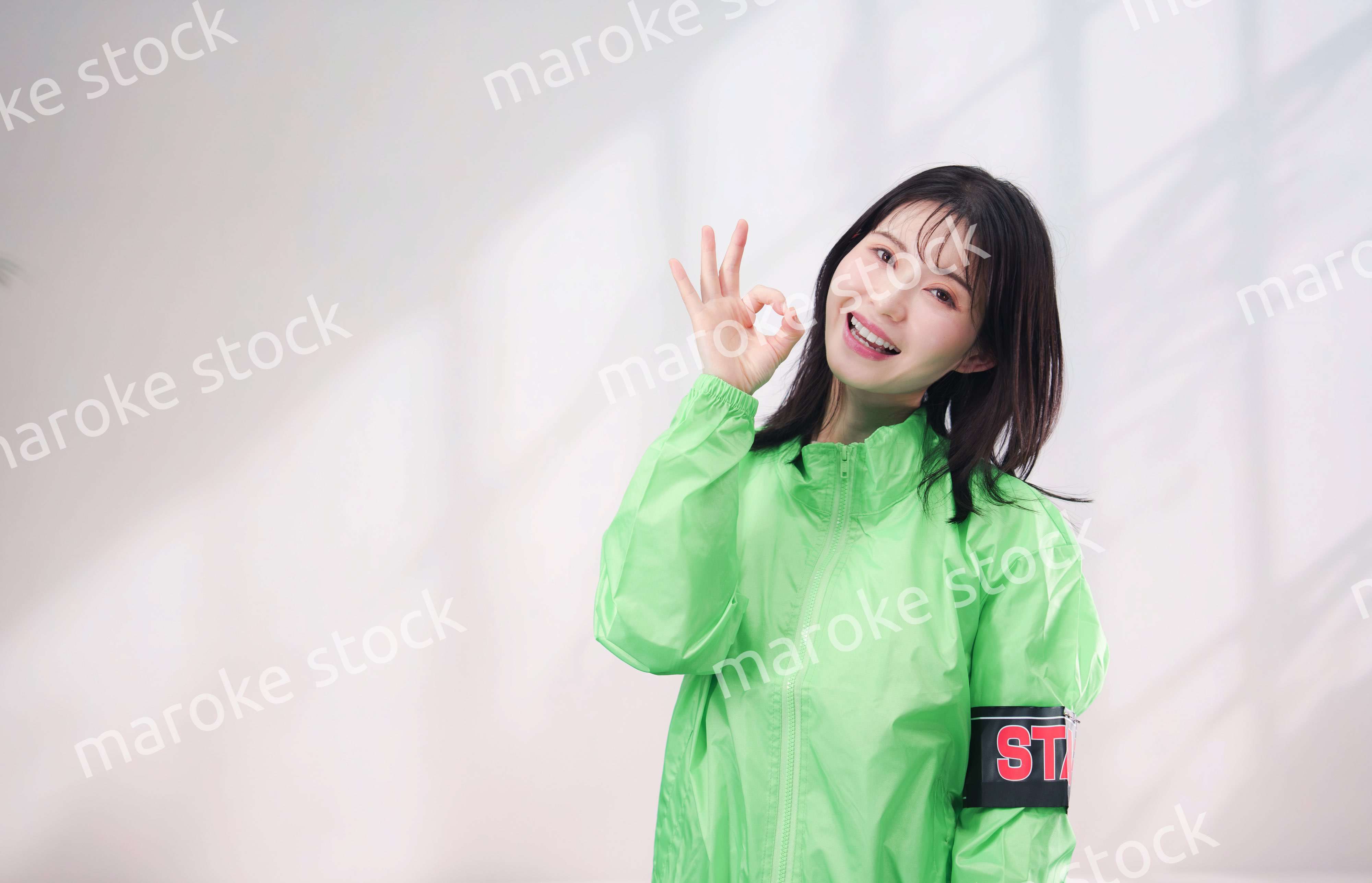 スタッフジャンパーをきた笑顔のイベントスタッフ（シンプル背景）