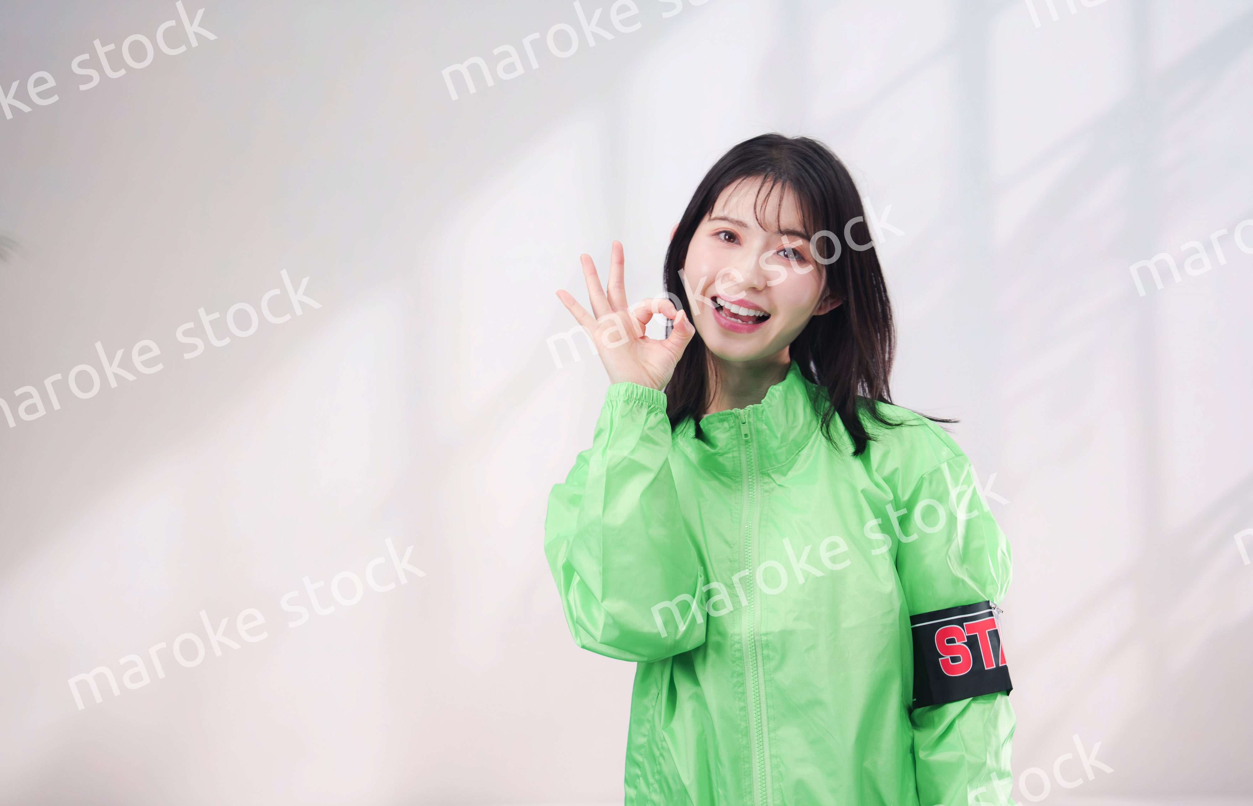 スタッフジャンパーをきた笑顔のイベントスタッフ（シンプル背景）