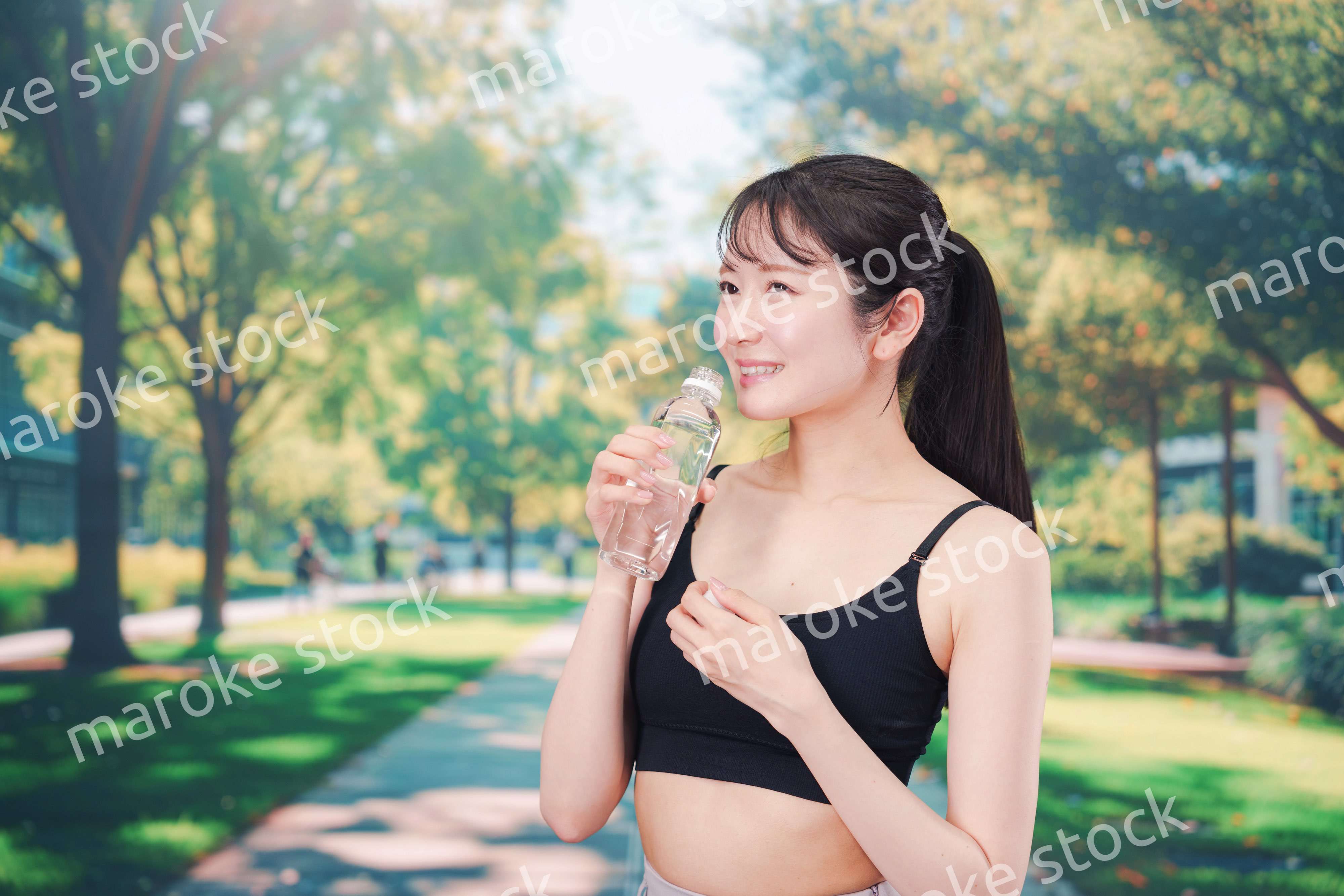 外でランニングをしながら水を飲む若い女性