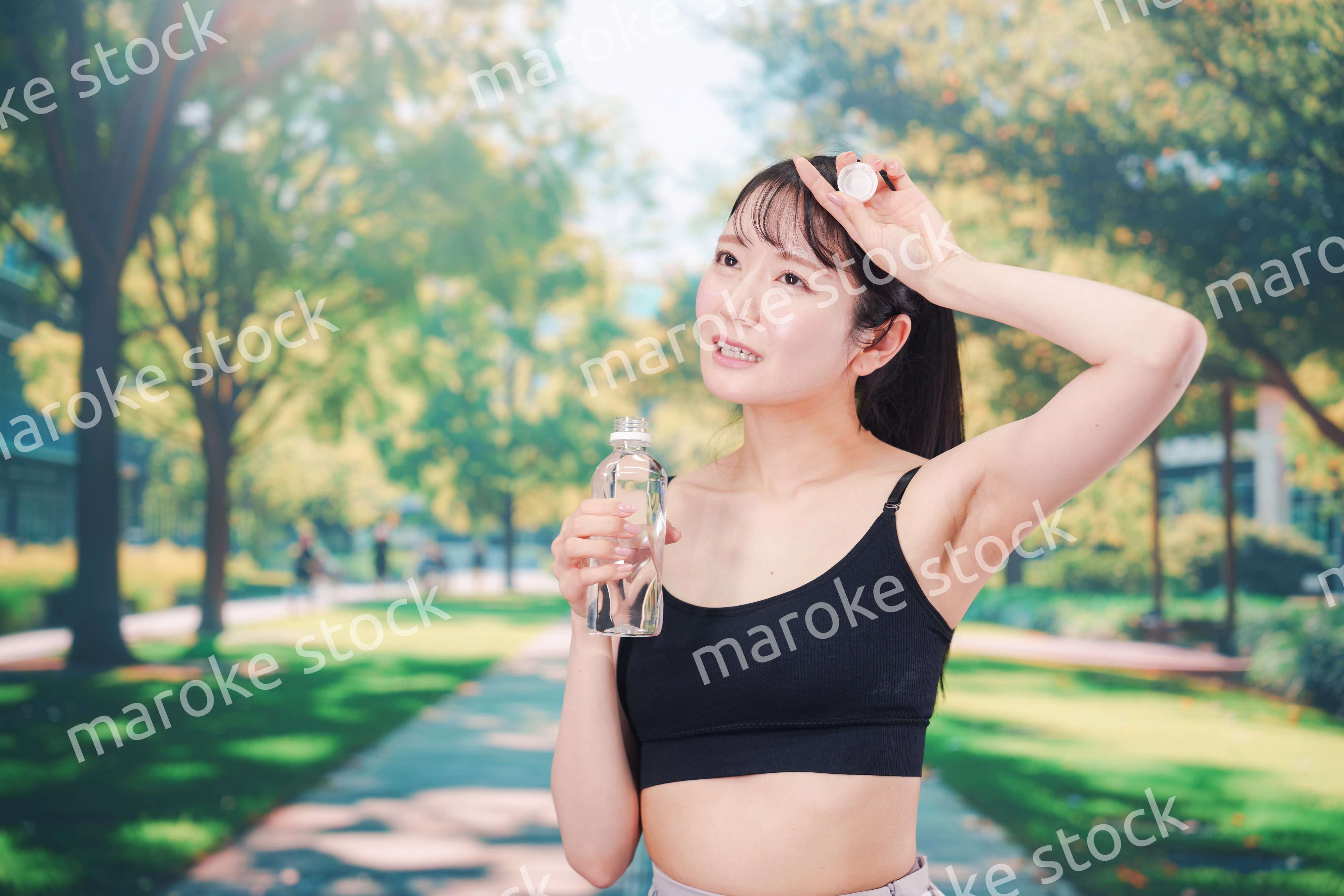 外でランニングをしながら水を飲む若い女性