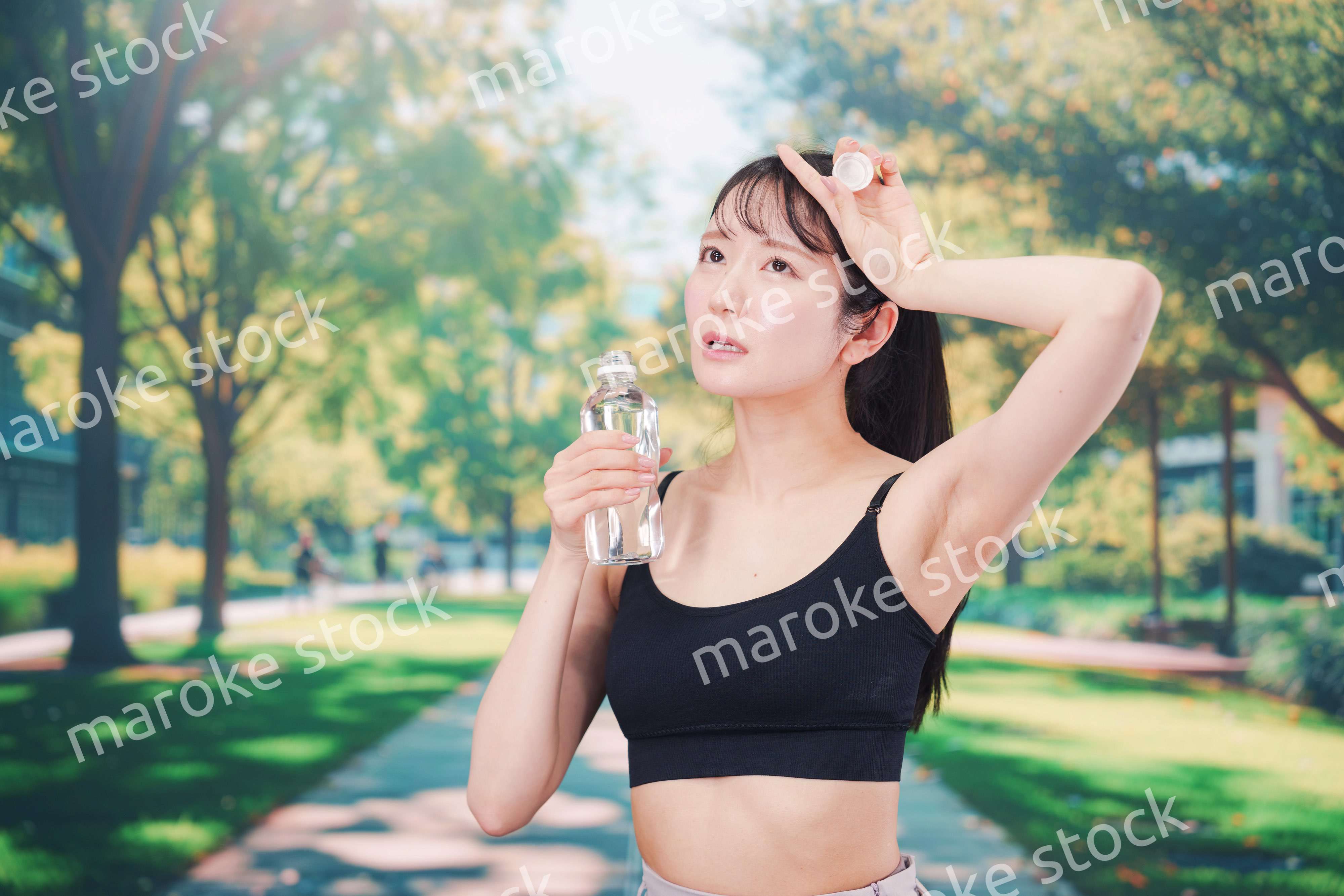 外でランニングをしながら水を飲む若い女性