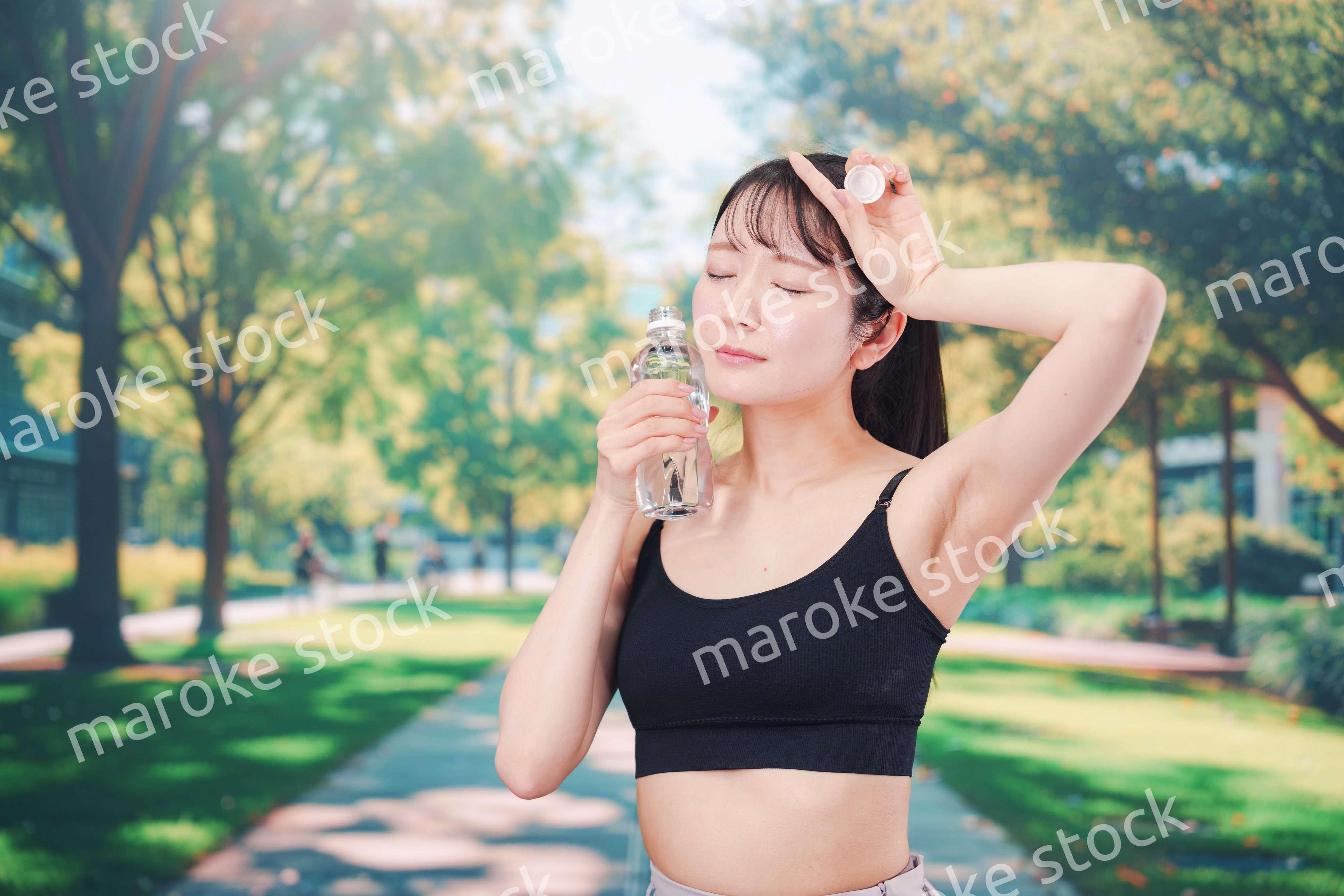 外でランニングをしながら水を飲む若い女性