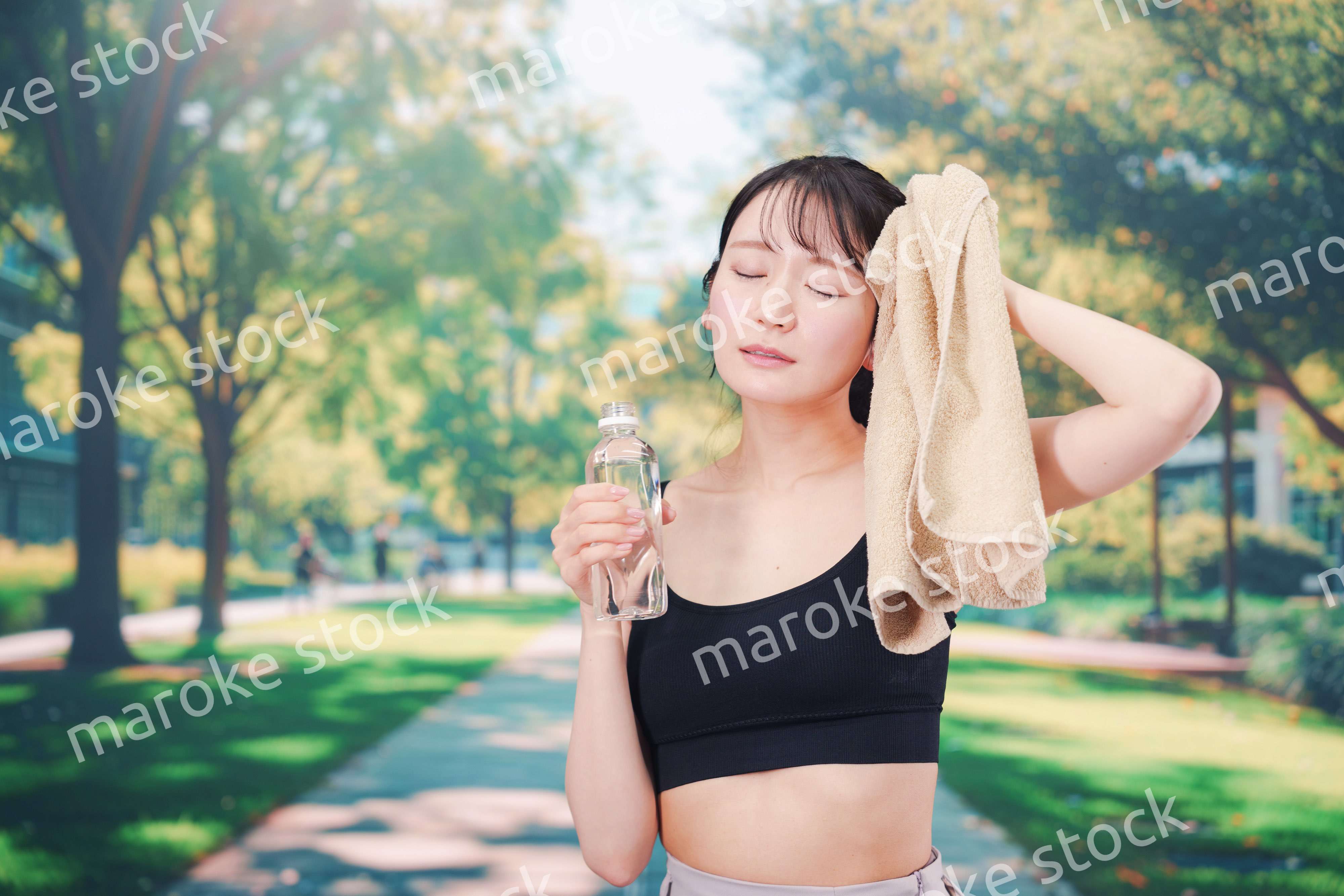 外でランニングをしながら水を飲む若い女性