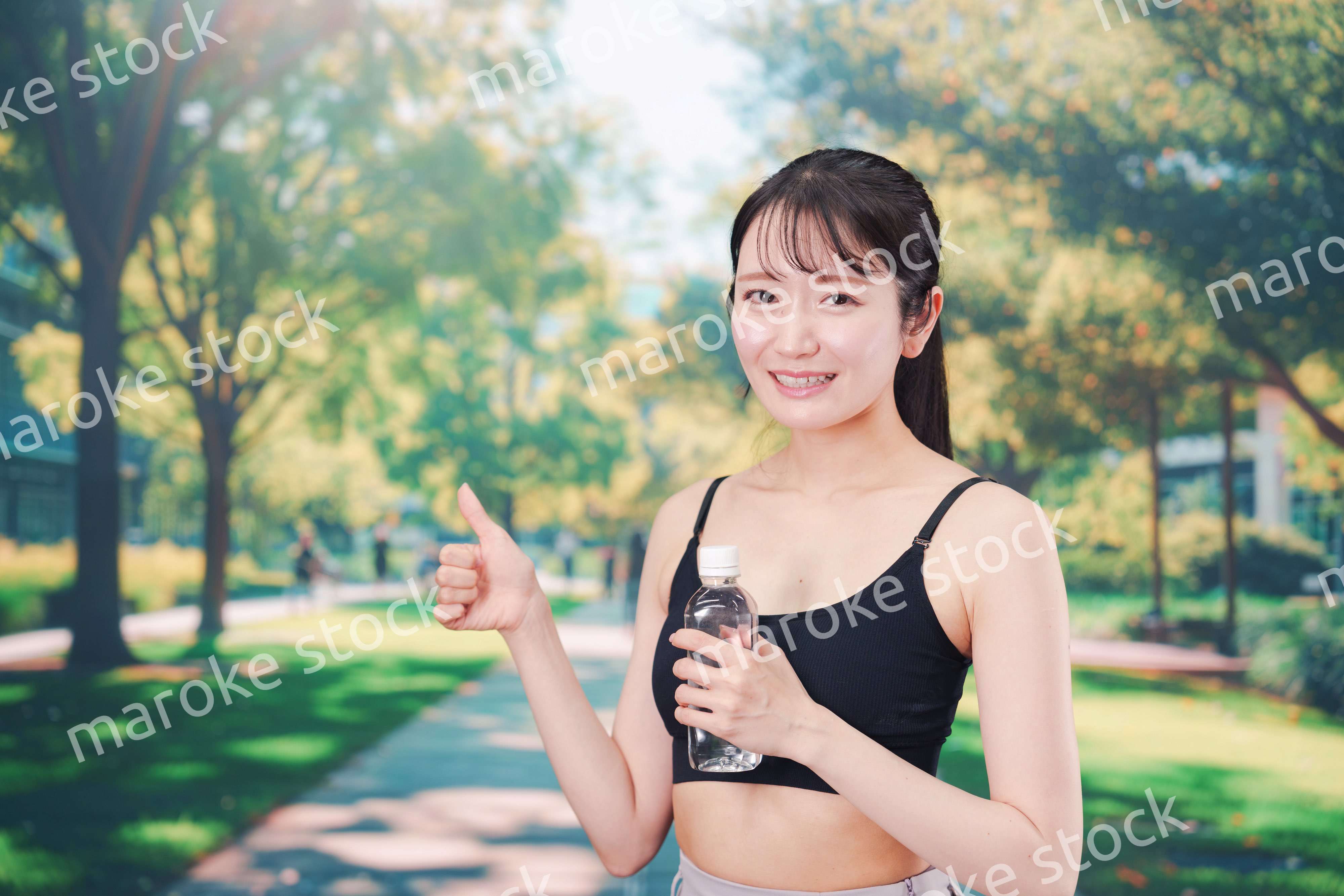 外でランニングをしながら水を飲む若い女性