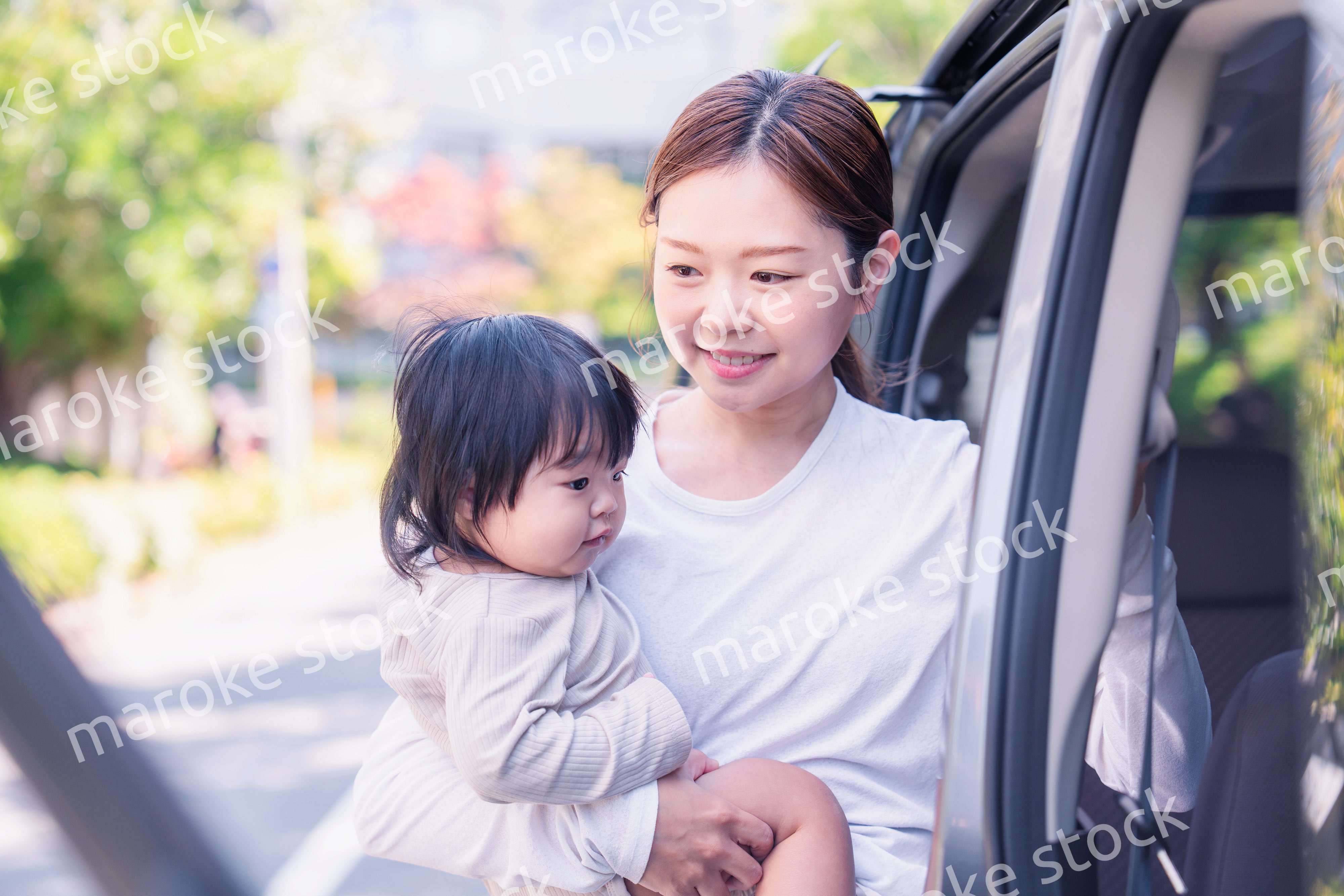 赤ちゃんと一緒に車に乗るお母さん