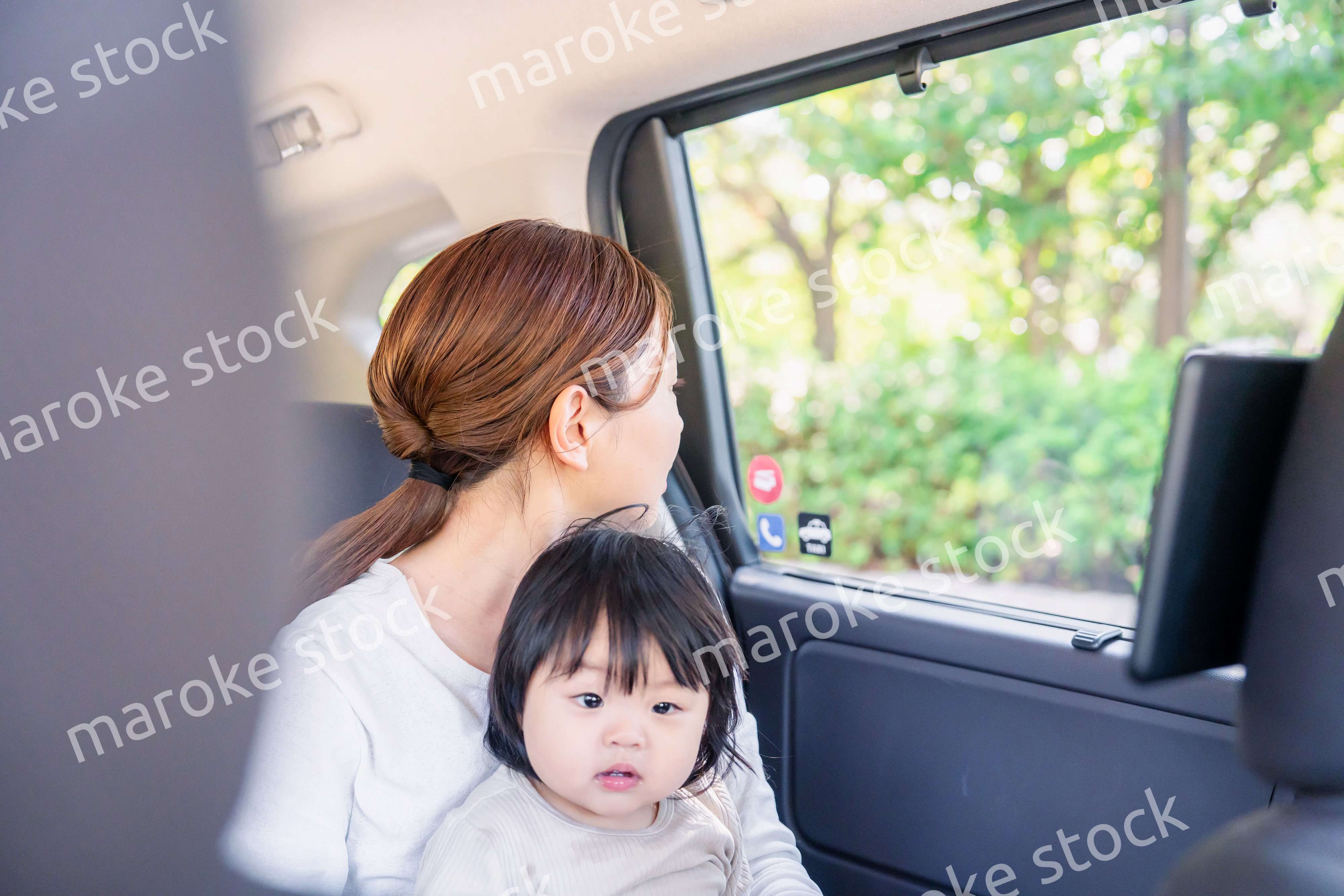 子どもと一緒にタクシーに乗って外を眺めるお母さん