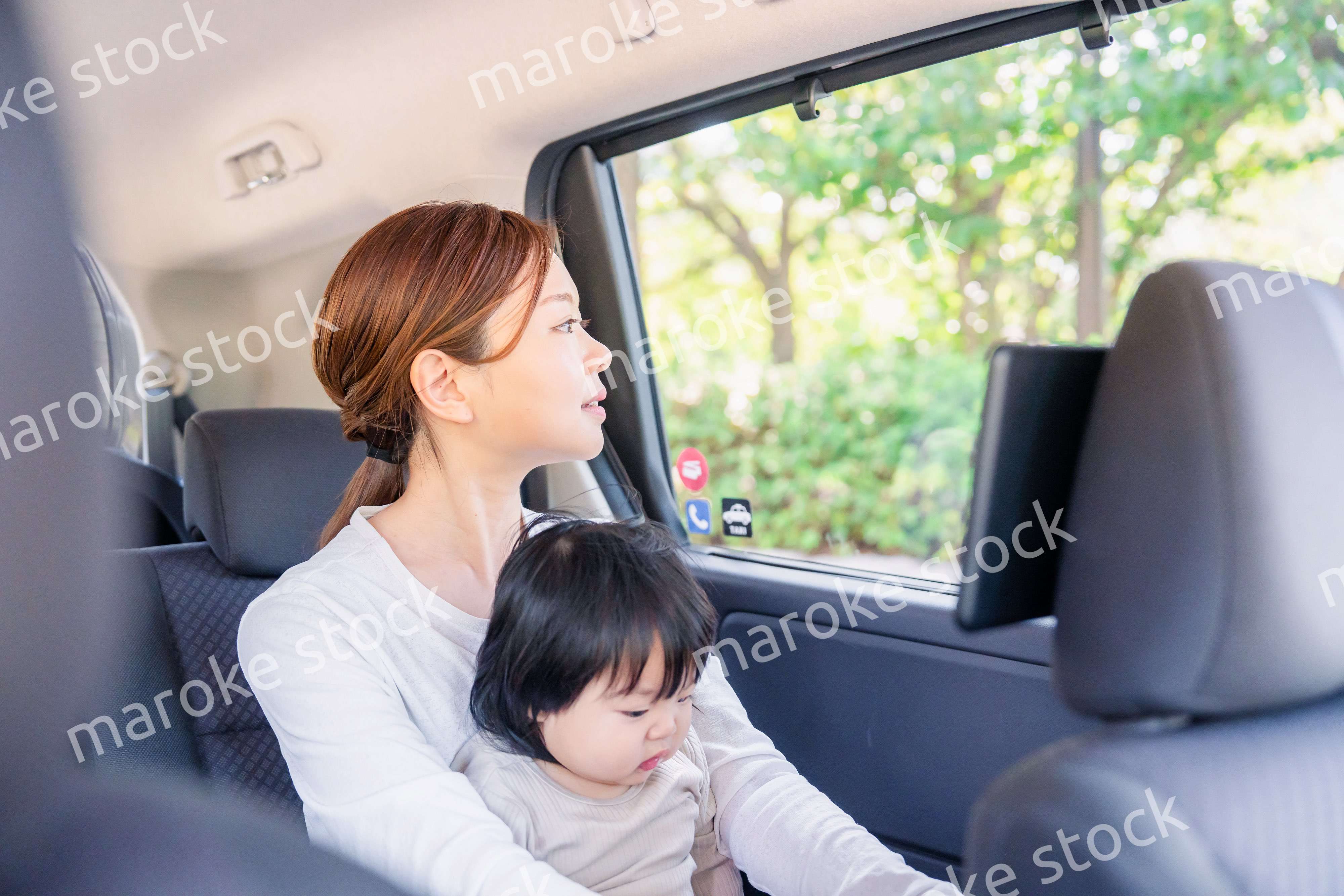 子どもと一緒にタクシーに乗って外を眺めるお母さん