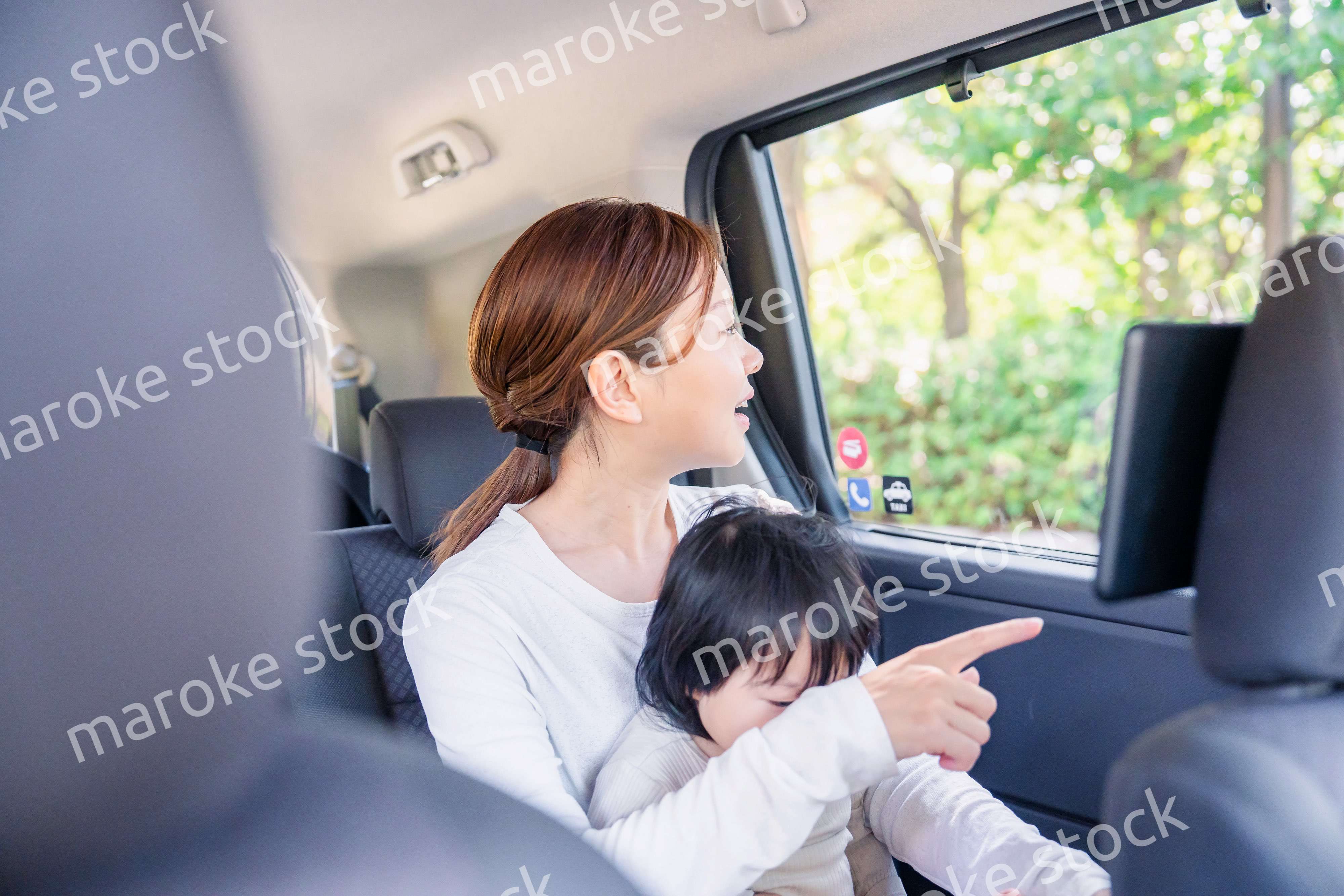 子どもと一緒にタクシーに乗って外を眺めるお母さん