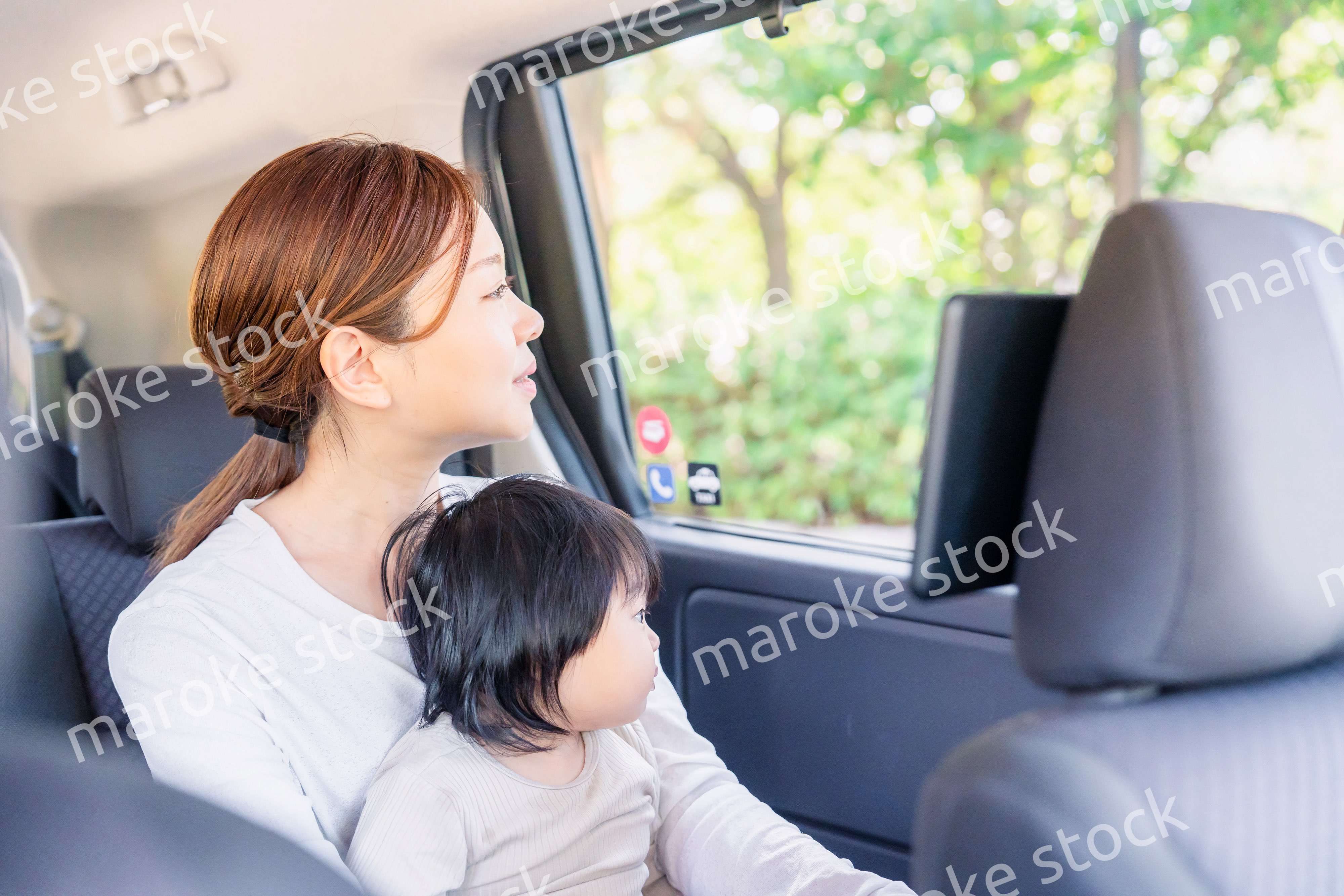 子どもと一緒にタクシーに乗って外を眺めるお母さん