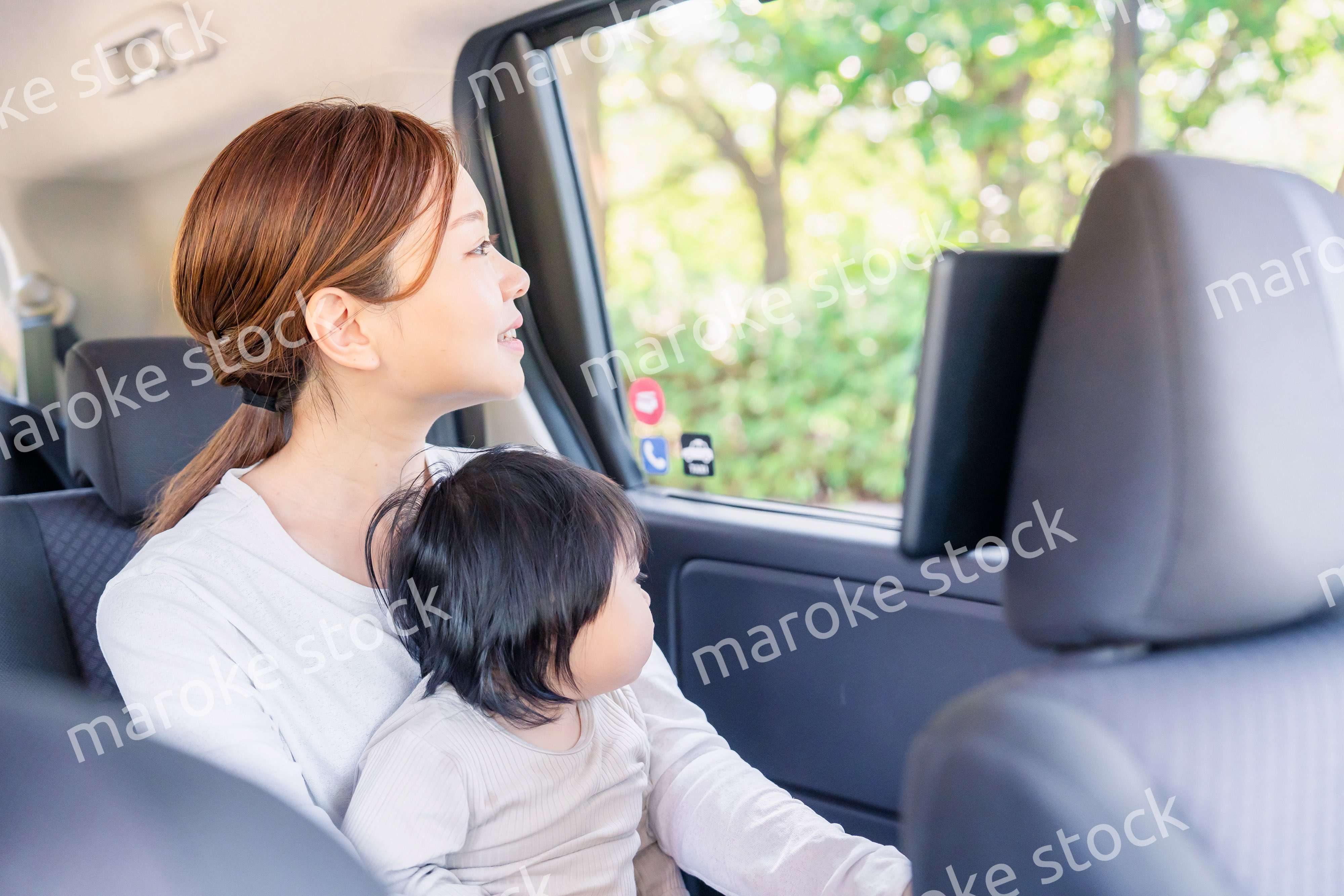 子どもと一緒にタクシーに乗って外を眺めるお母さん