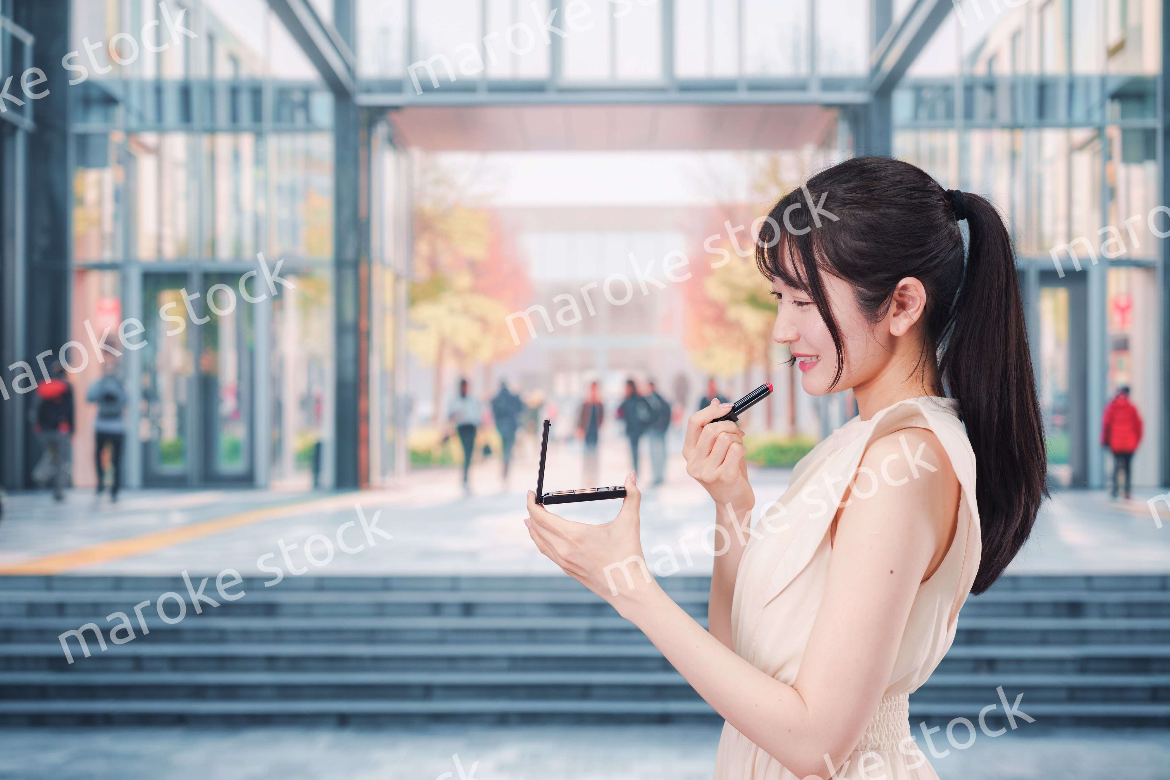 大学のキャンパスでお化粧をする大学生の女性