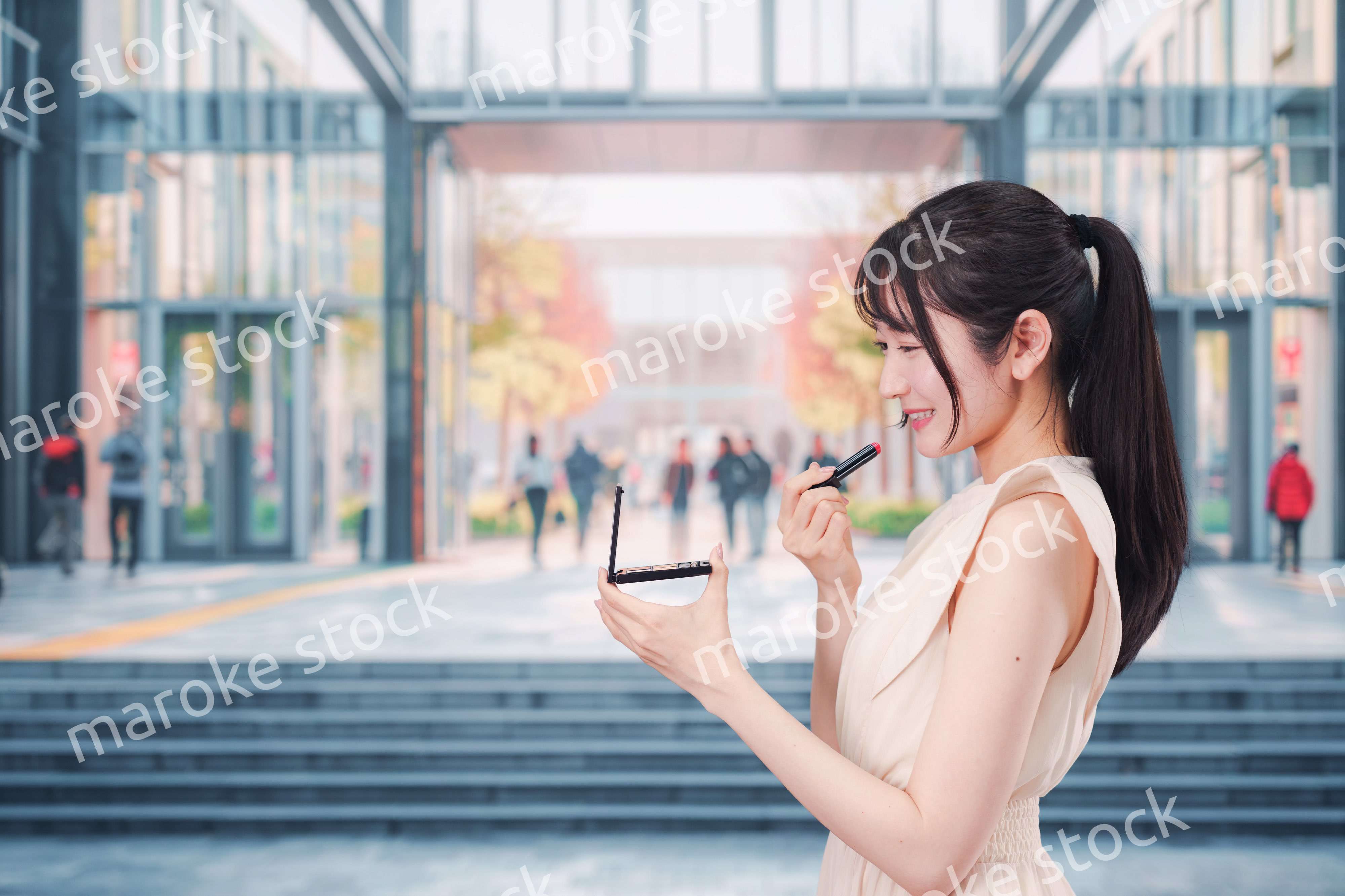 大学のキャンパスでお化粧をする大学生の女性