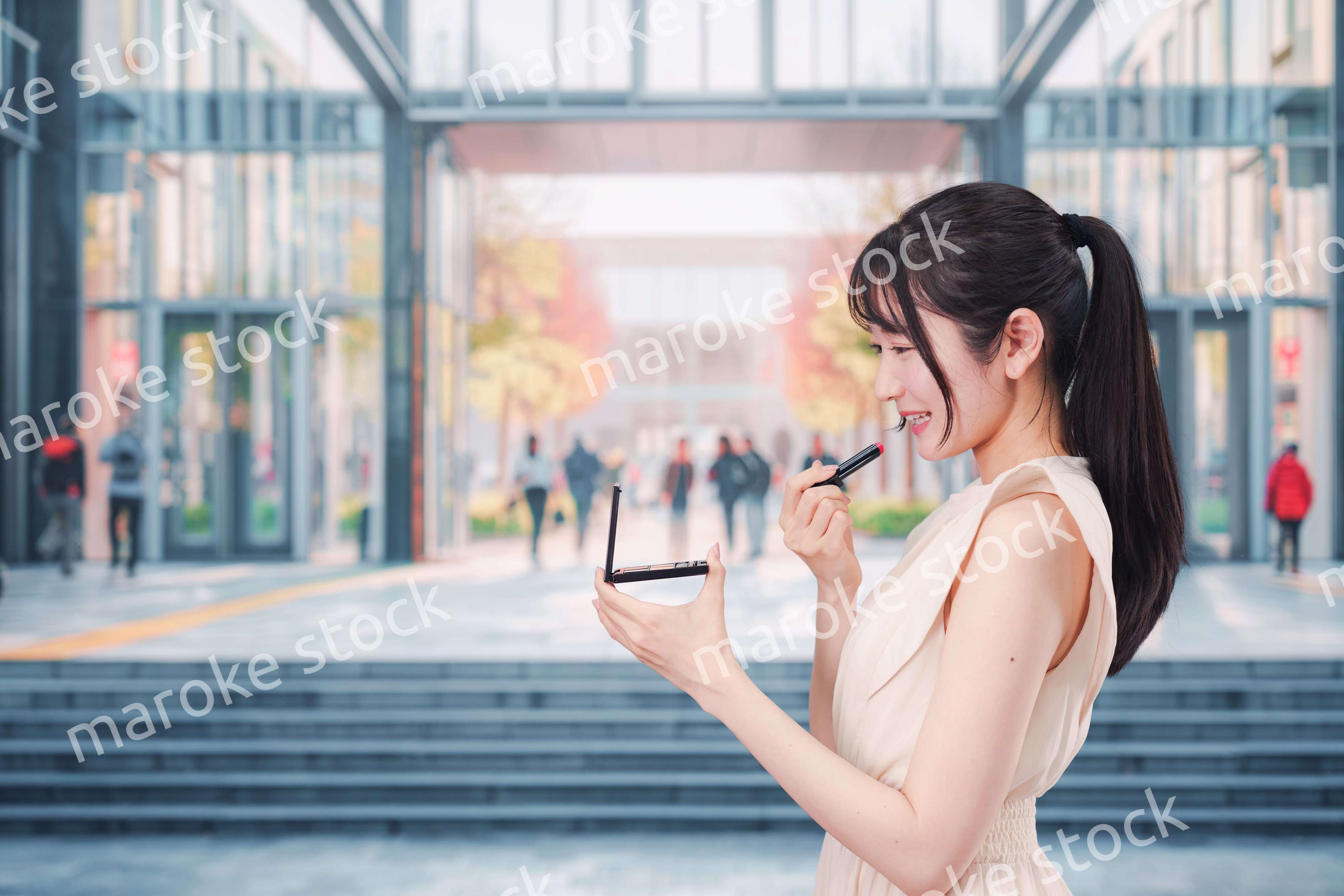 大学のキャンパスでお化粧をする大学生の女性