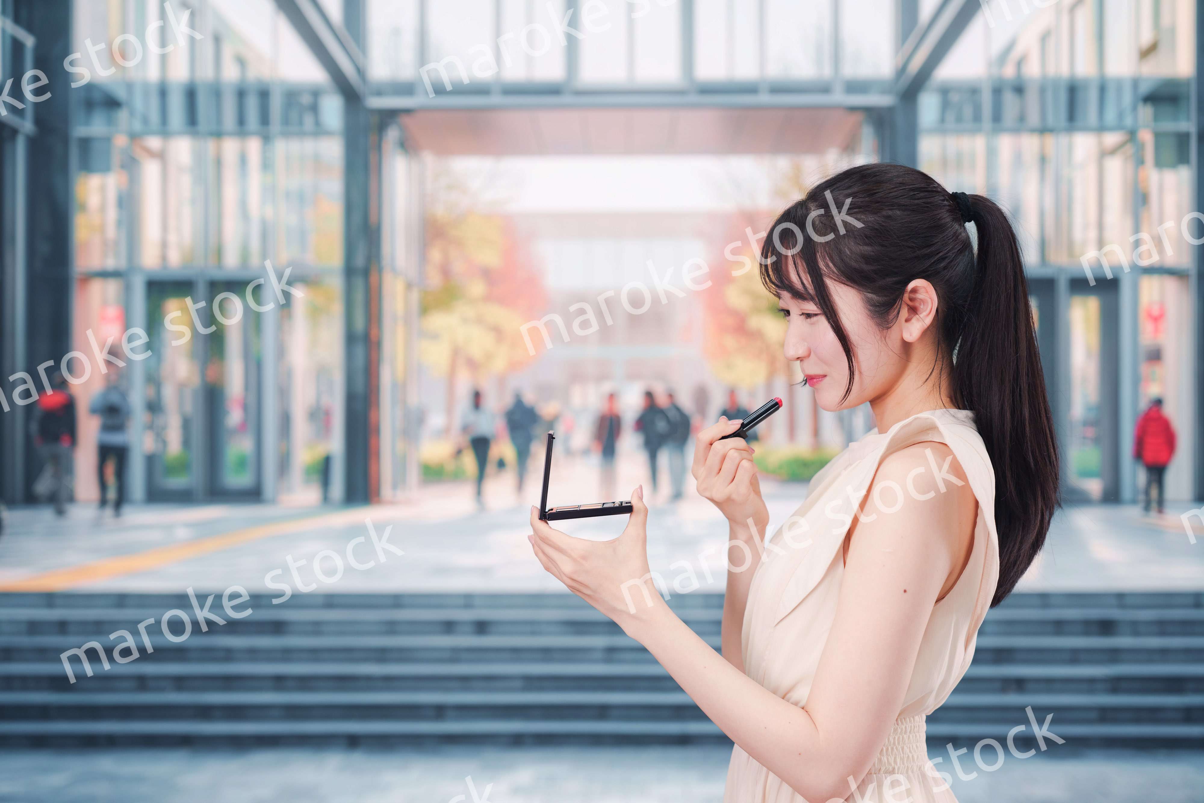 大学のキャンパスでお化粧をする大学生の女性