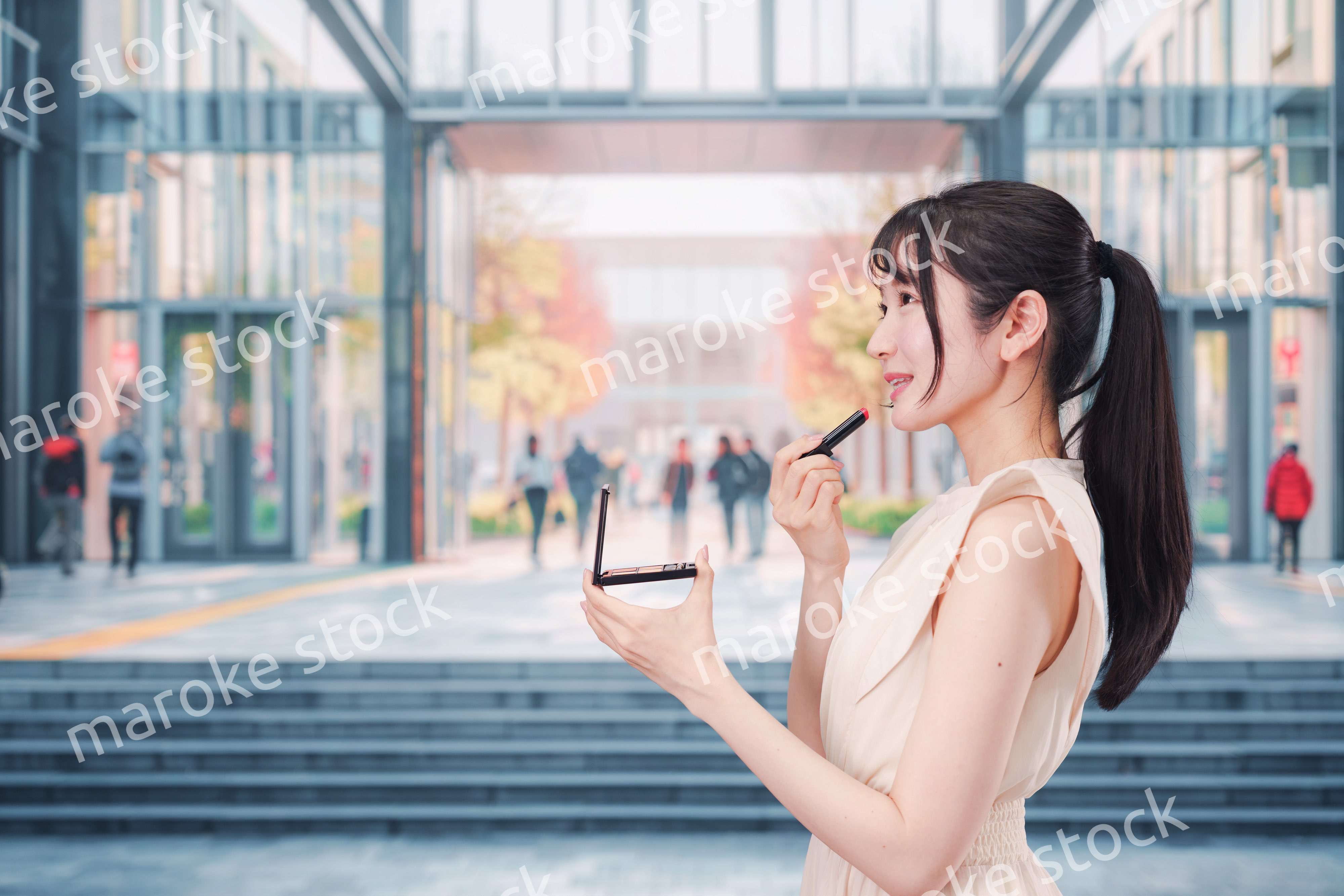 大学のキャンパスでお化粧をする大学生の女性