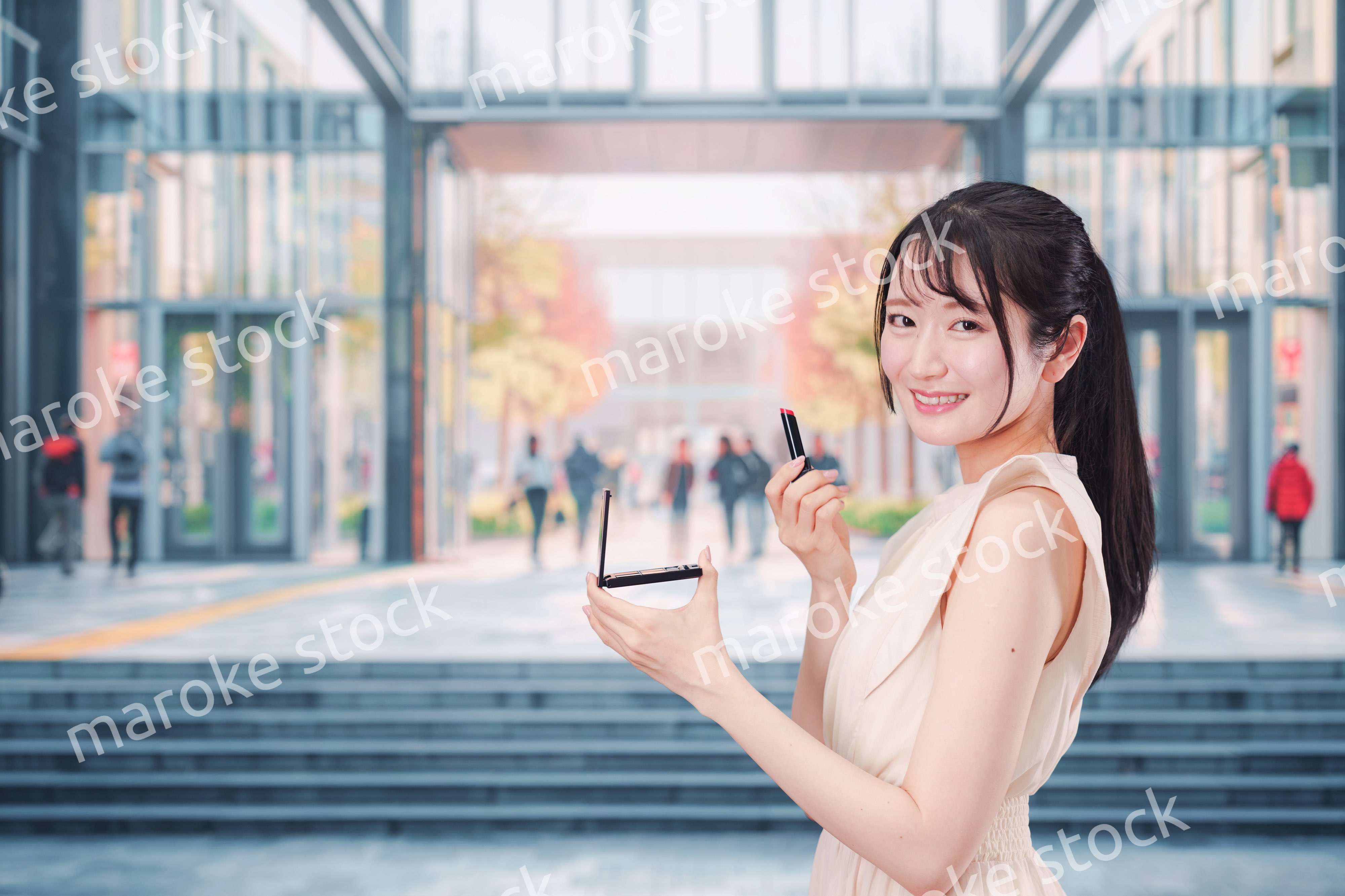 大学のキャンパスでお化粧をする大学生の女性