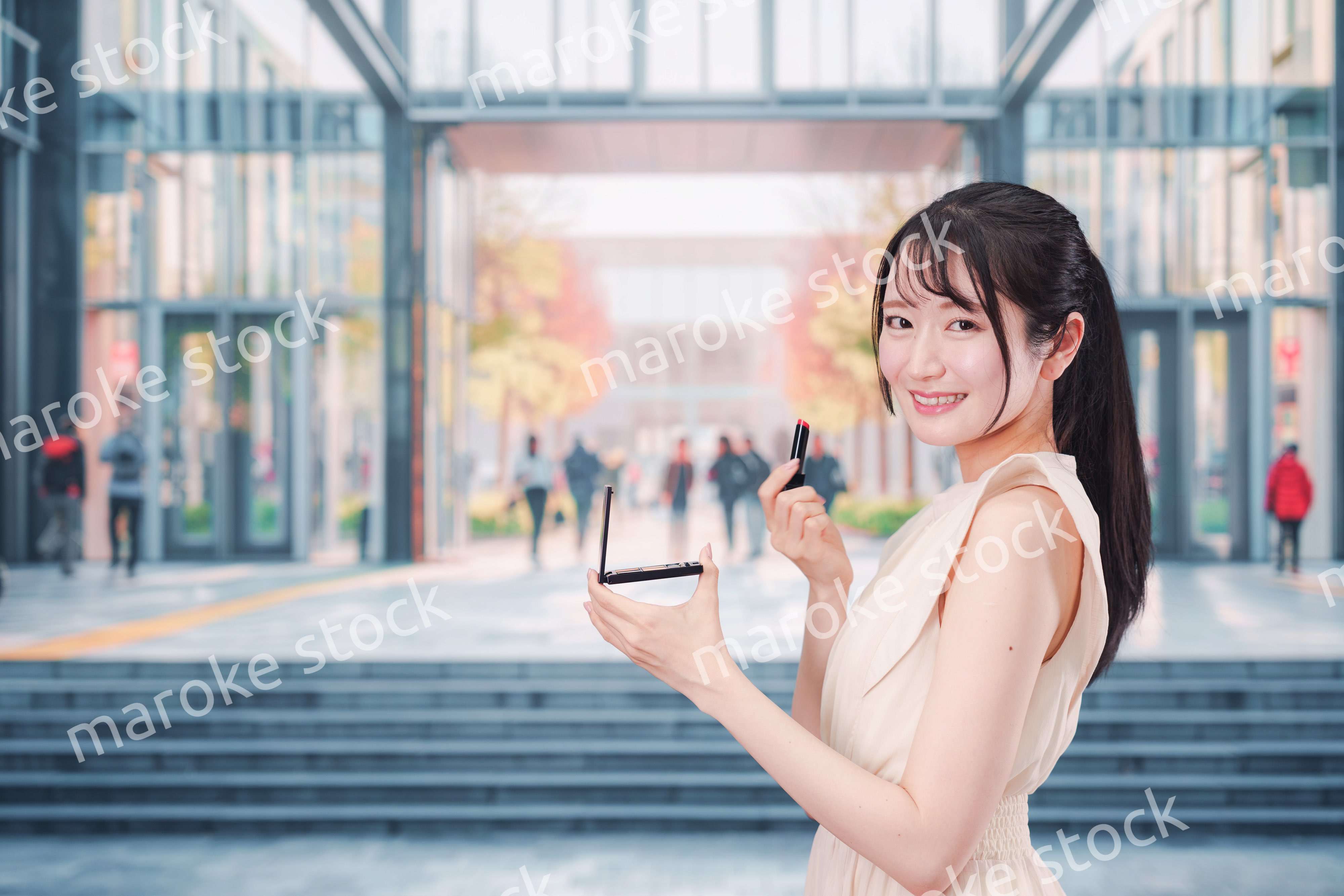 大学のキャンパスでお化粧をする大学生の女性