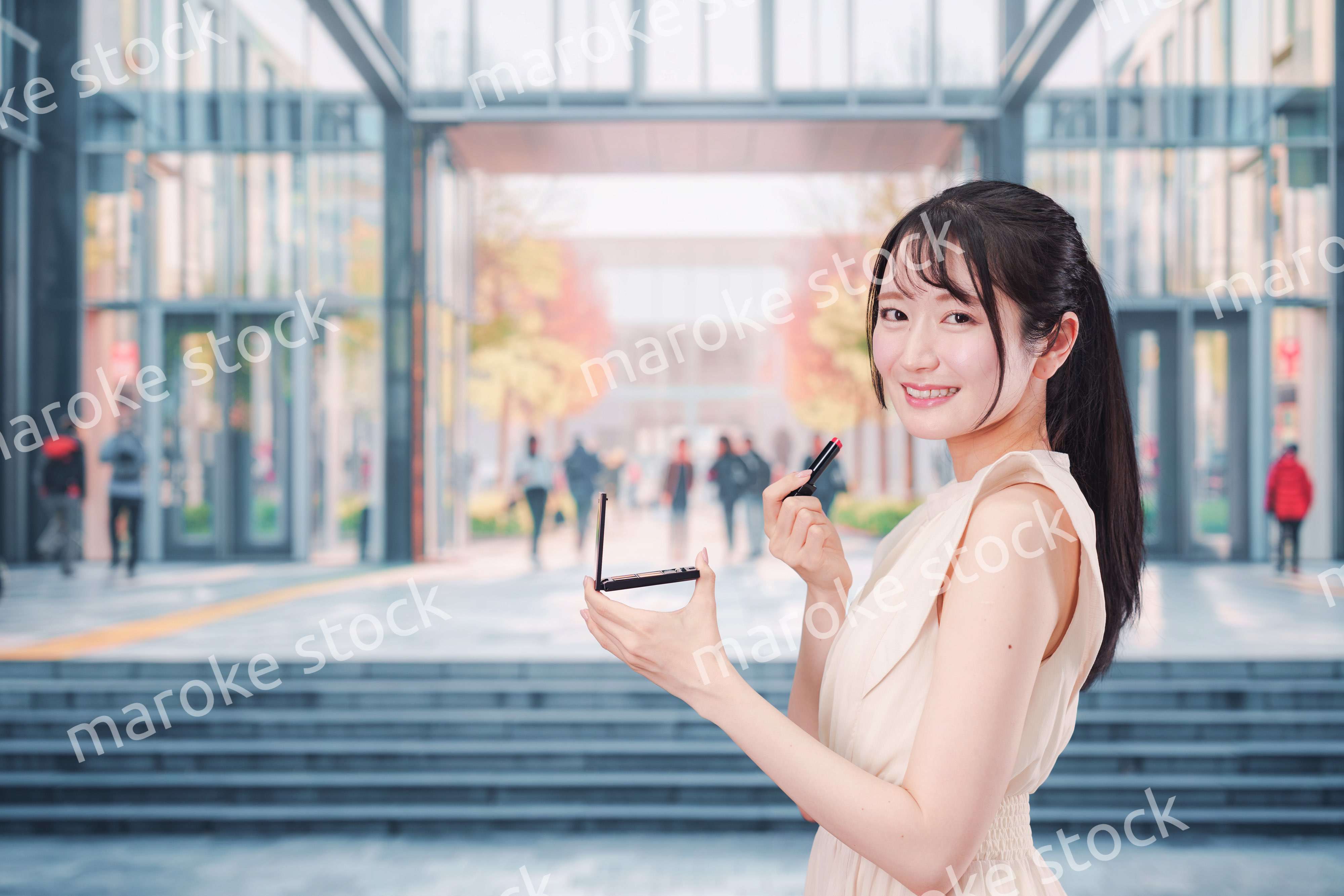 大学のキャンパスでお化粧をする大学生の女性