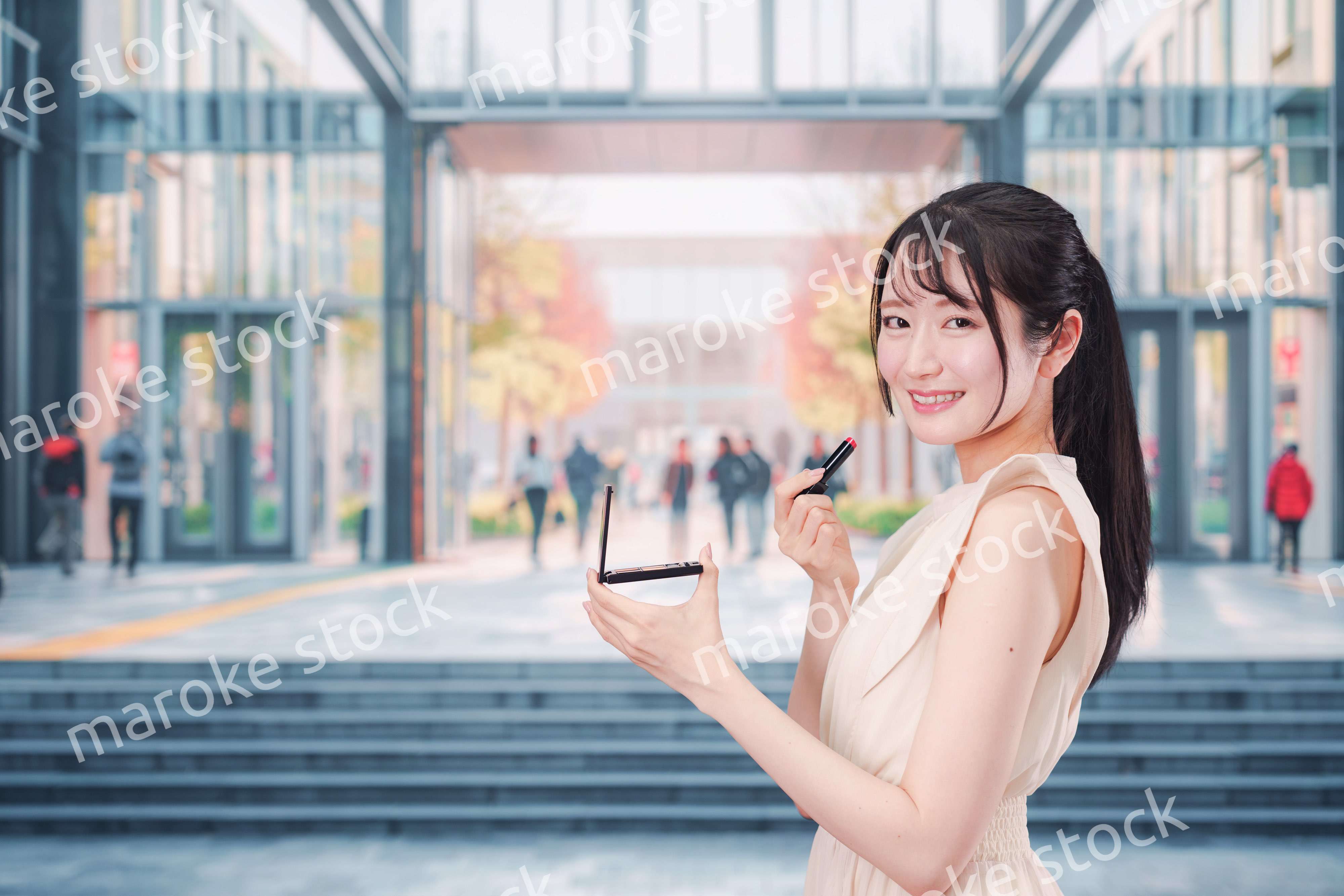 大学のキャンパスでお化粧をする大学生の女性