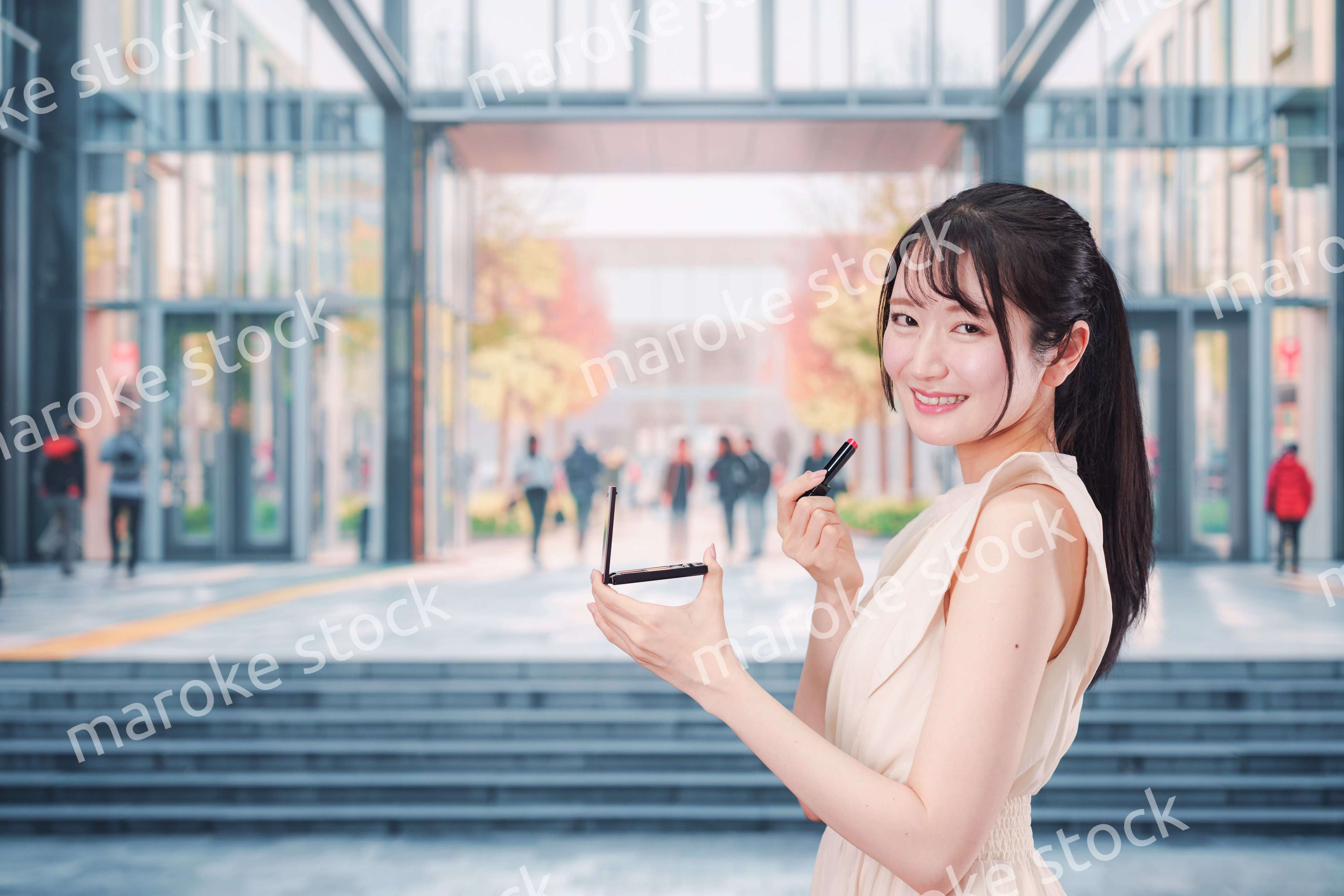 大学のキャンパスでお化粧をする大学生の女性