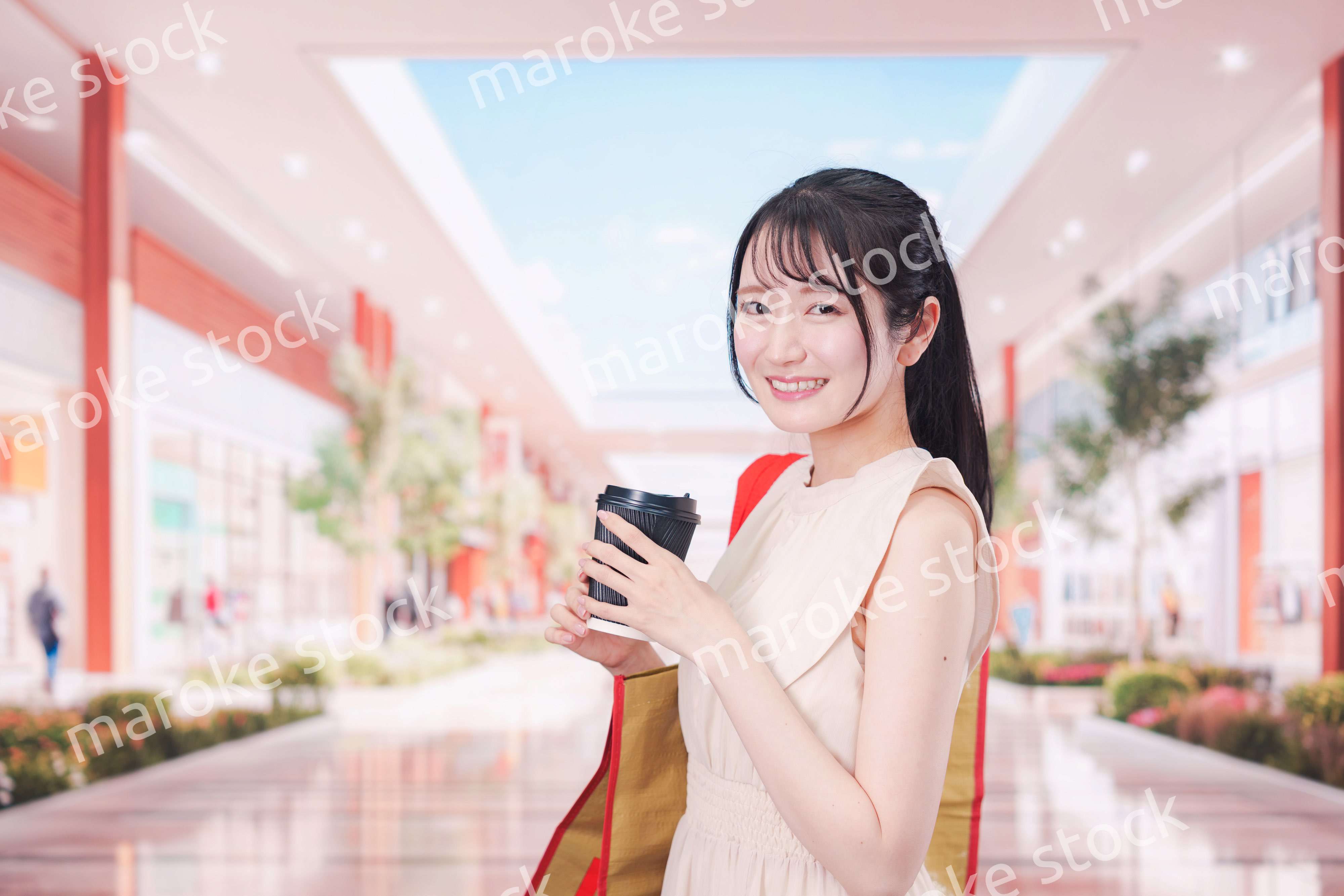 コーヒーを飲みながらショッピングモールで買い物をする女性