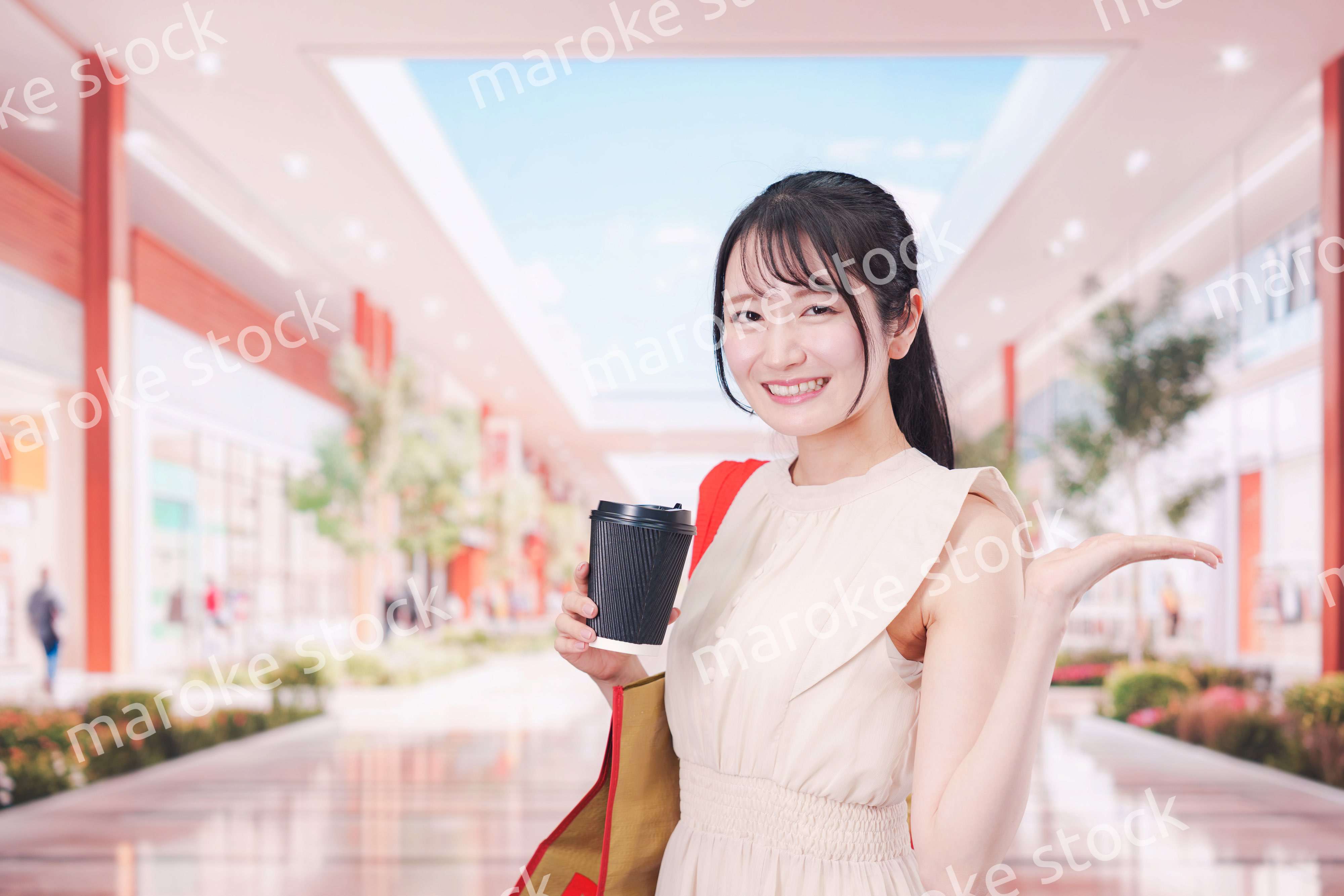 コーヒーを飲みながらショッピングモールで買い物をする女性