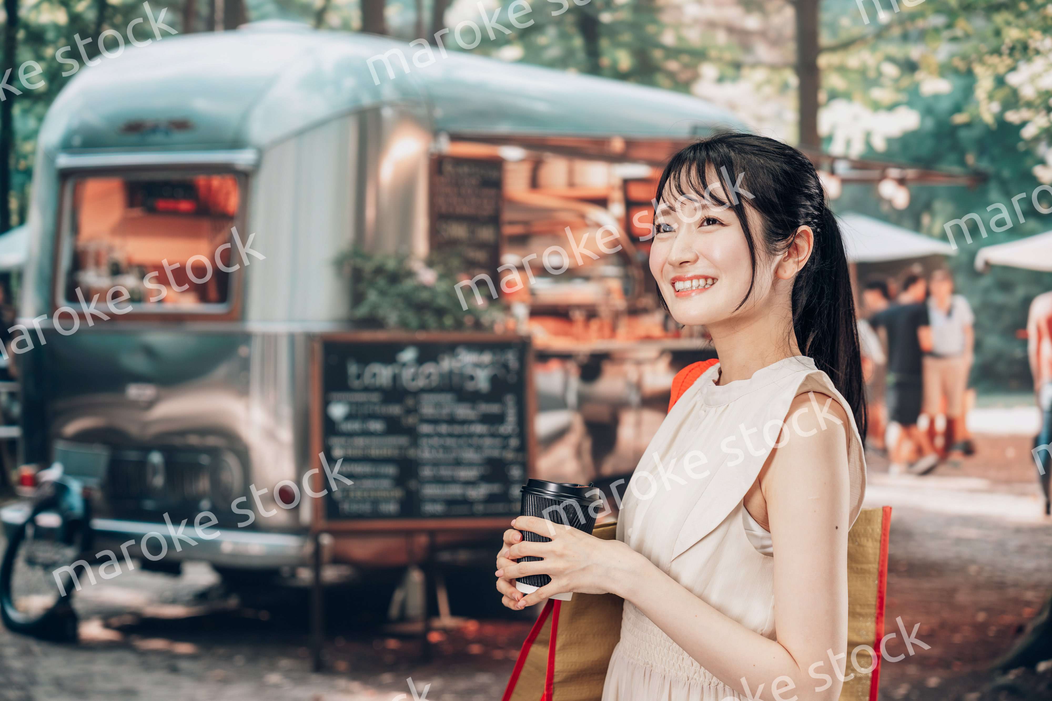 屋外のマーケットプレイスで飲食を楽しむ若い女性