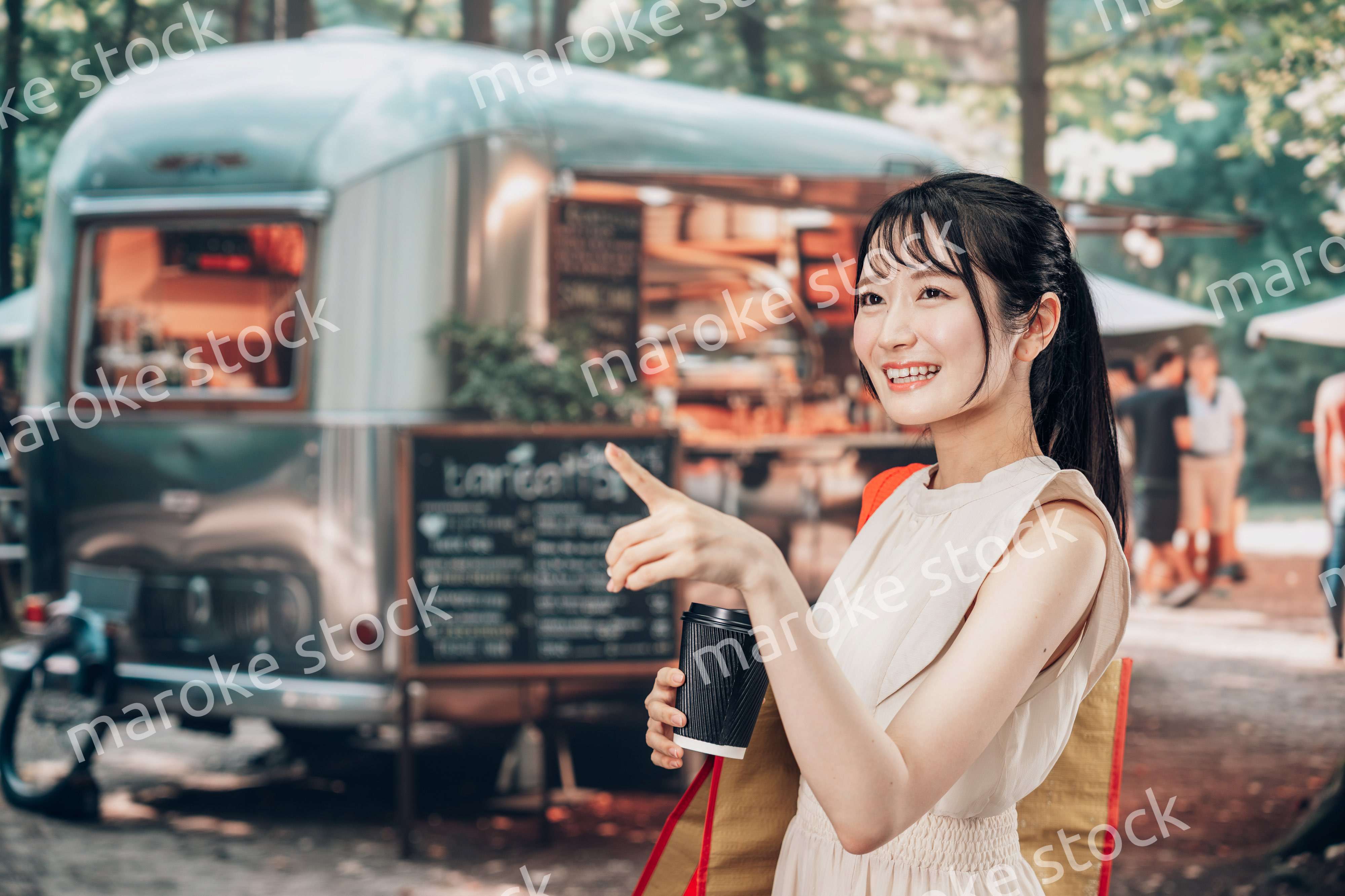 屋外のマーケットプレイスで飲食を楽しむ若い女性