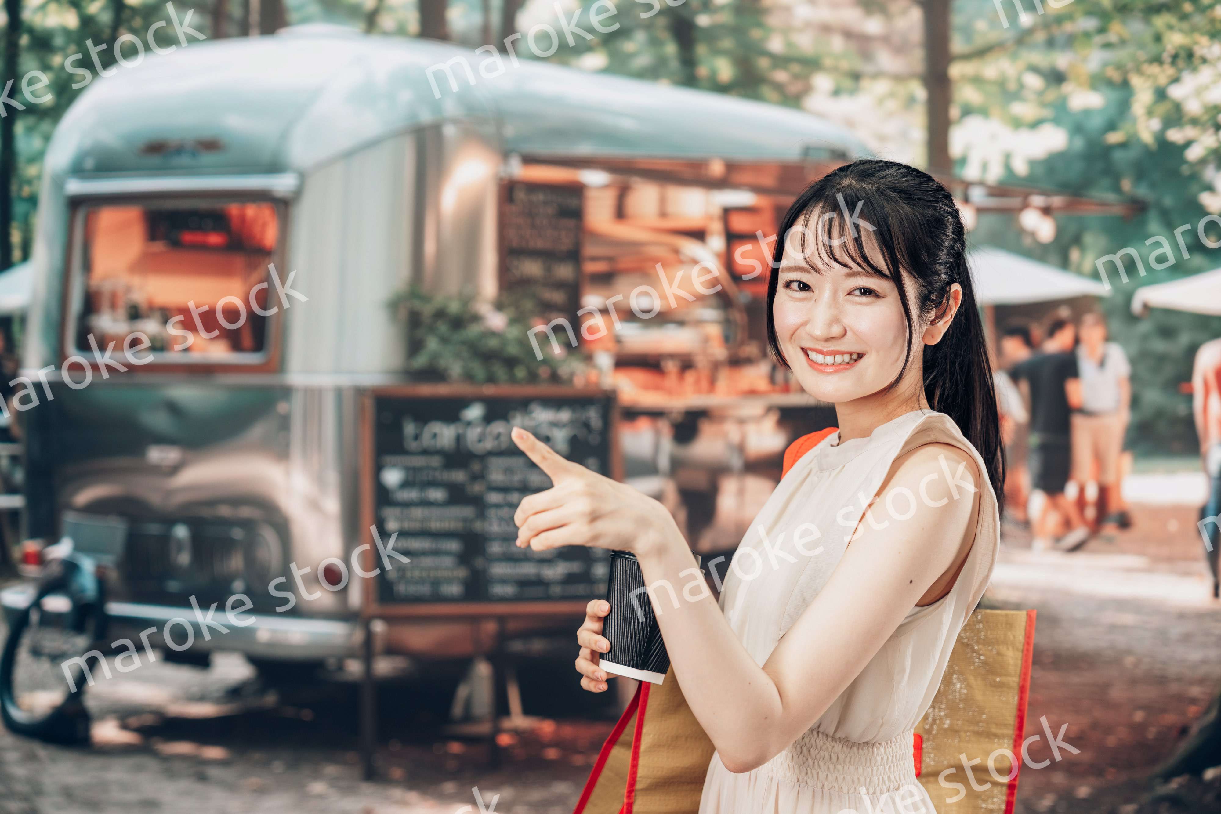 屋外のマーケットプレイスで飲食を楽しむ若い女性