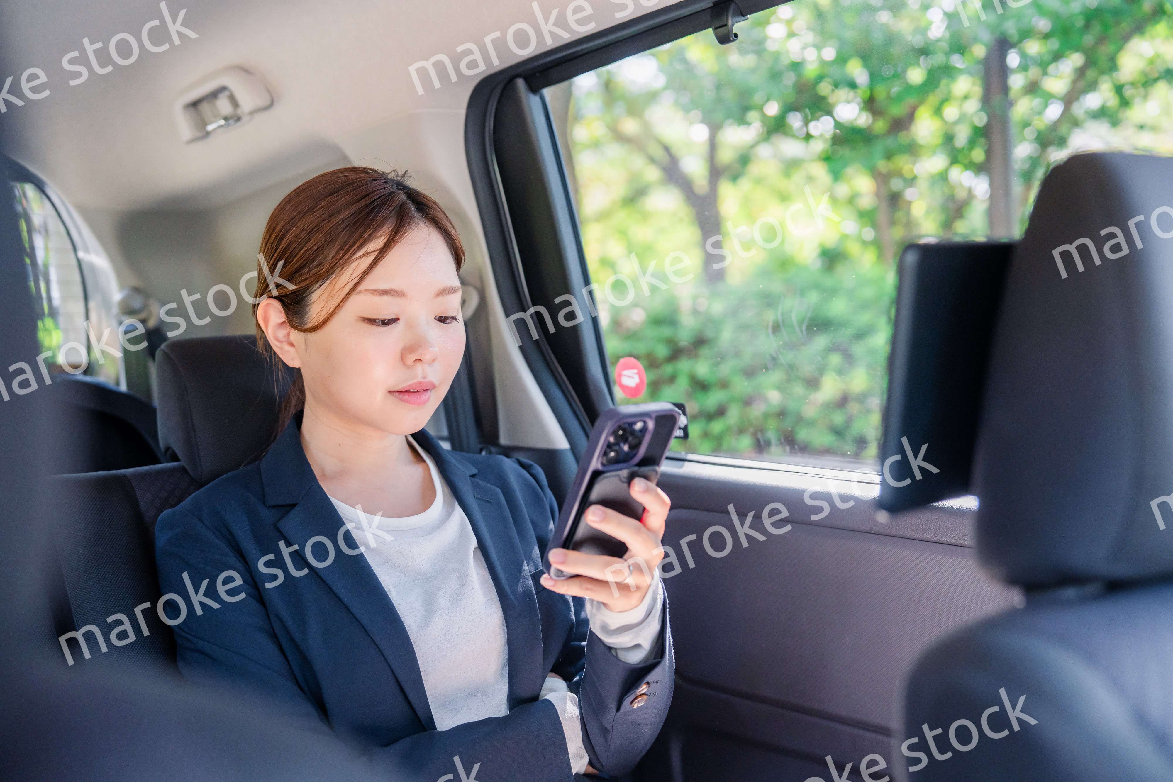 タクシーでスマホを使う若い女性ビジネスパーソン